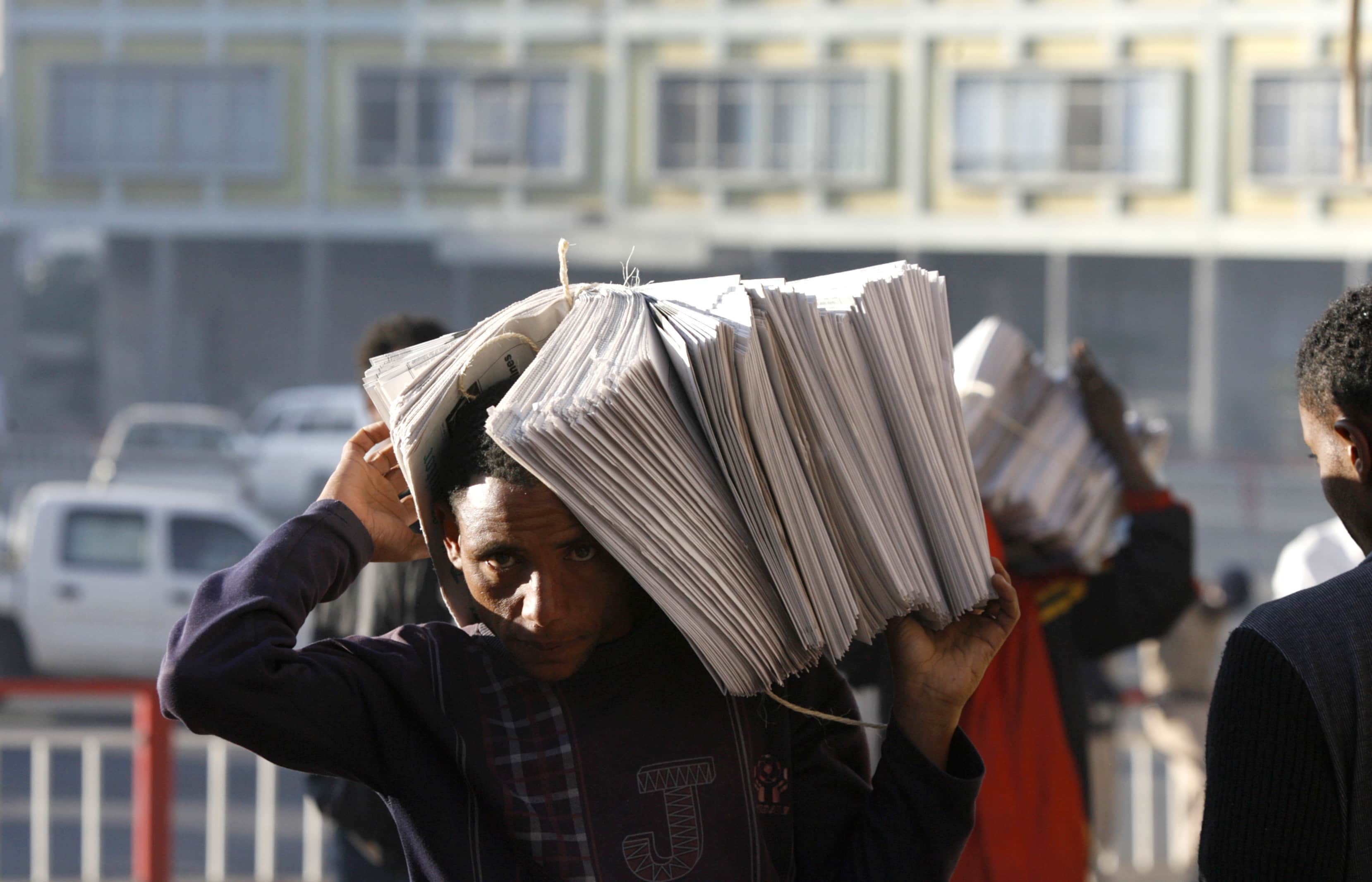 Vendors carry piles of newspapers along a street in Addis Ababa, Reuters/Thomas Mukoya