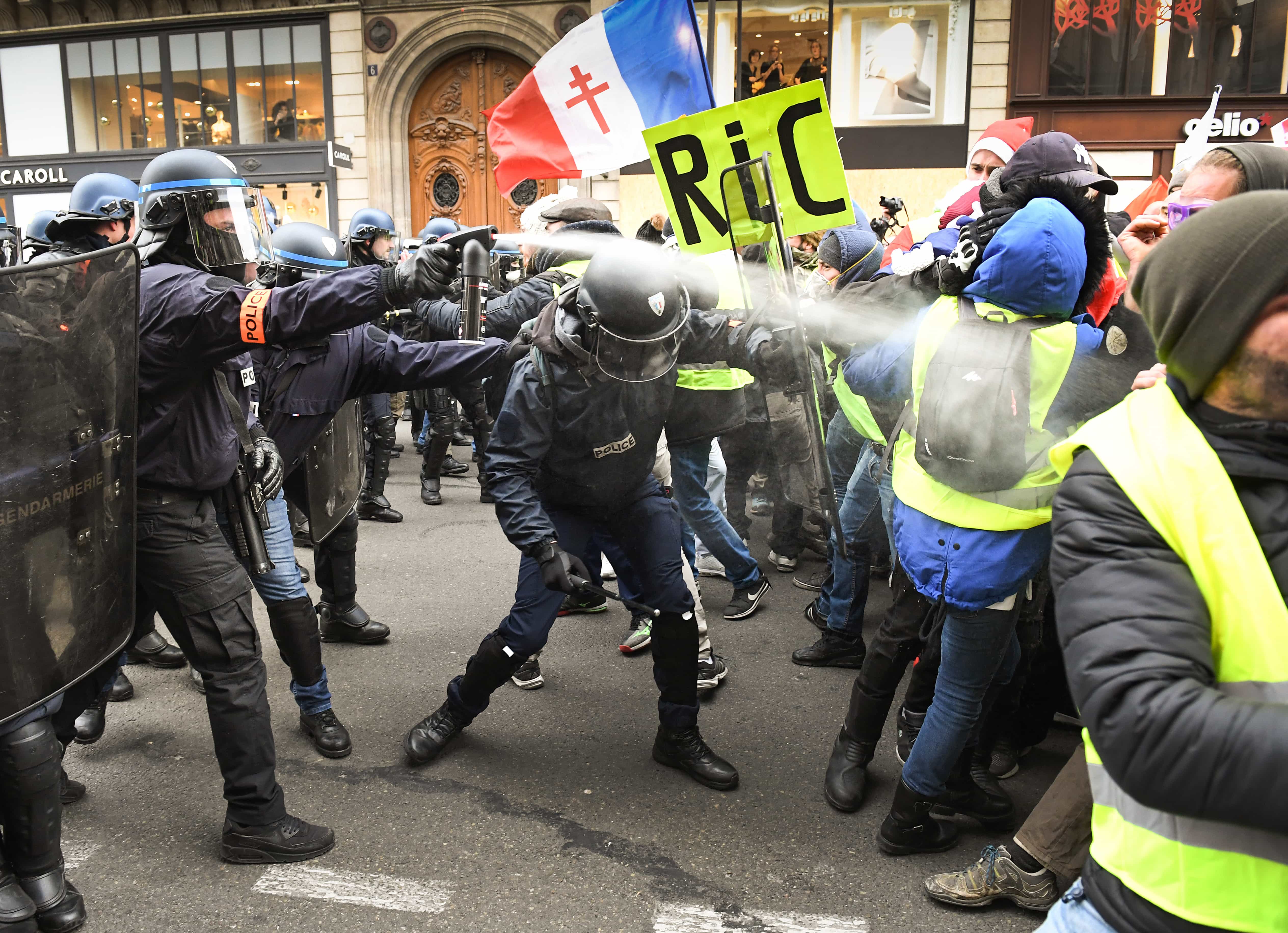 Police use tear gas on protesters holding a placard with the letters 'RIC' Referendum d'Initiatives Citoyennes (referendum based on popular initiative) during the 'yellow vests' demonstration in Paris, France, 15 December 2018, Jeff J Mitchell/Getty Images