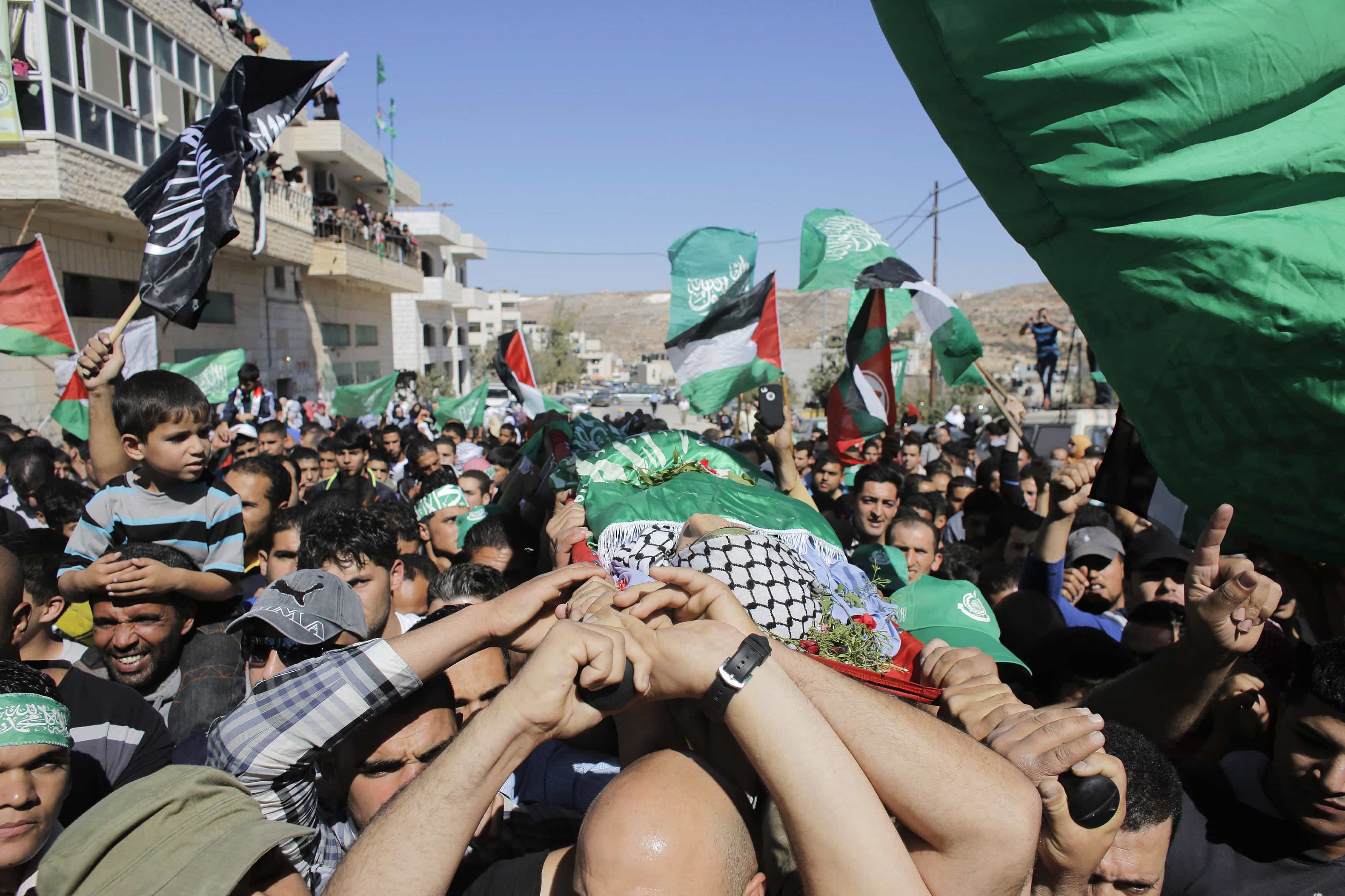 Mourners carry the body of Palestinian-American youth Orwah Hammad, whom medics said was killed by Israeli forces, during his funeral in the West Bank village of Silwad near Ramallah October 26, 2014, REUTERS/Ammar Awad