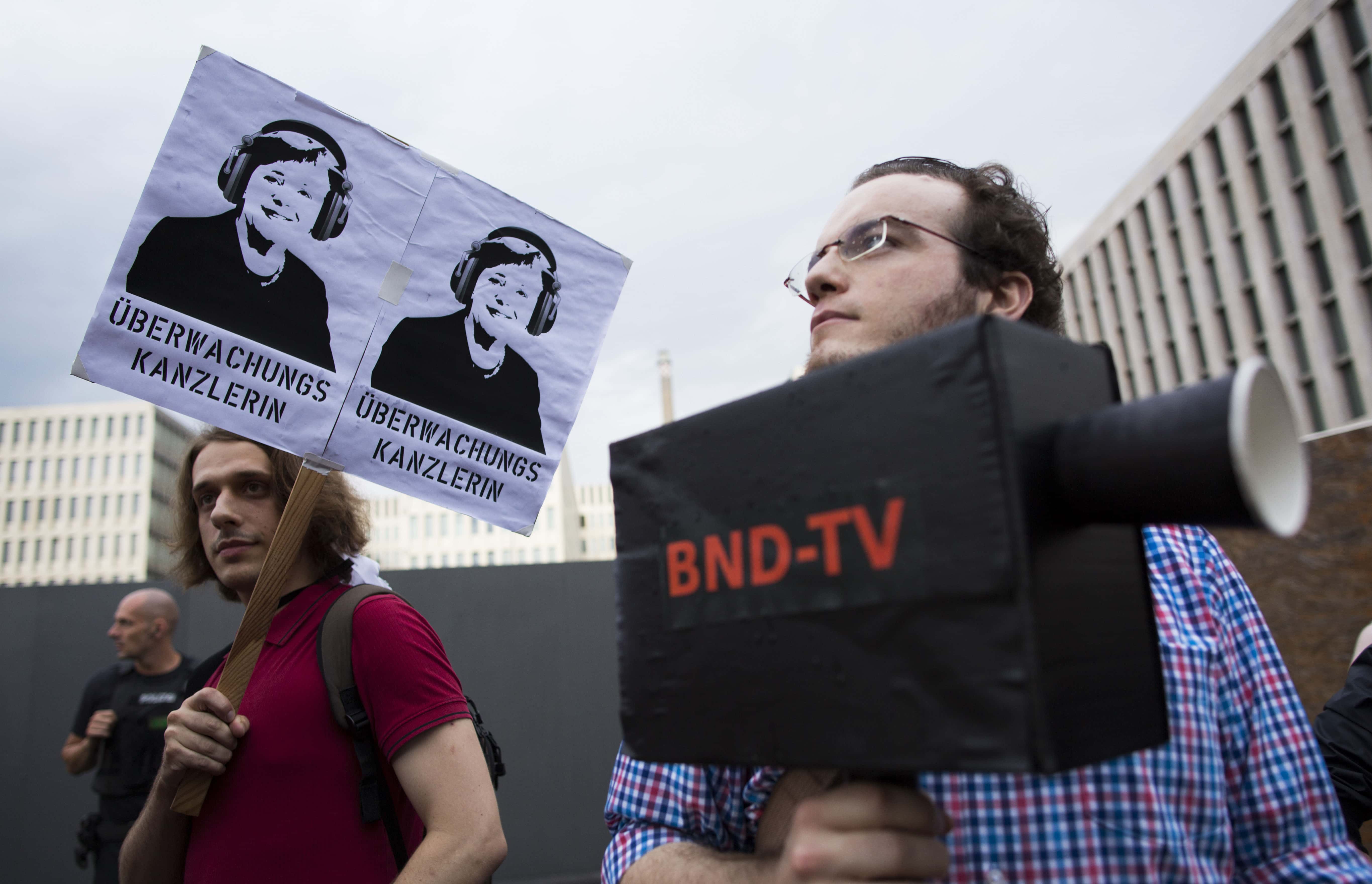 Demonstrators hold a poster showing a portrait of Angela Merkel reading "surveillance Chancellor" during a rally in front of the construction site of the headquarters of German intelligence agency in Berlin, 29 July 2013, AP Photo/Gero Breloer