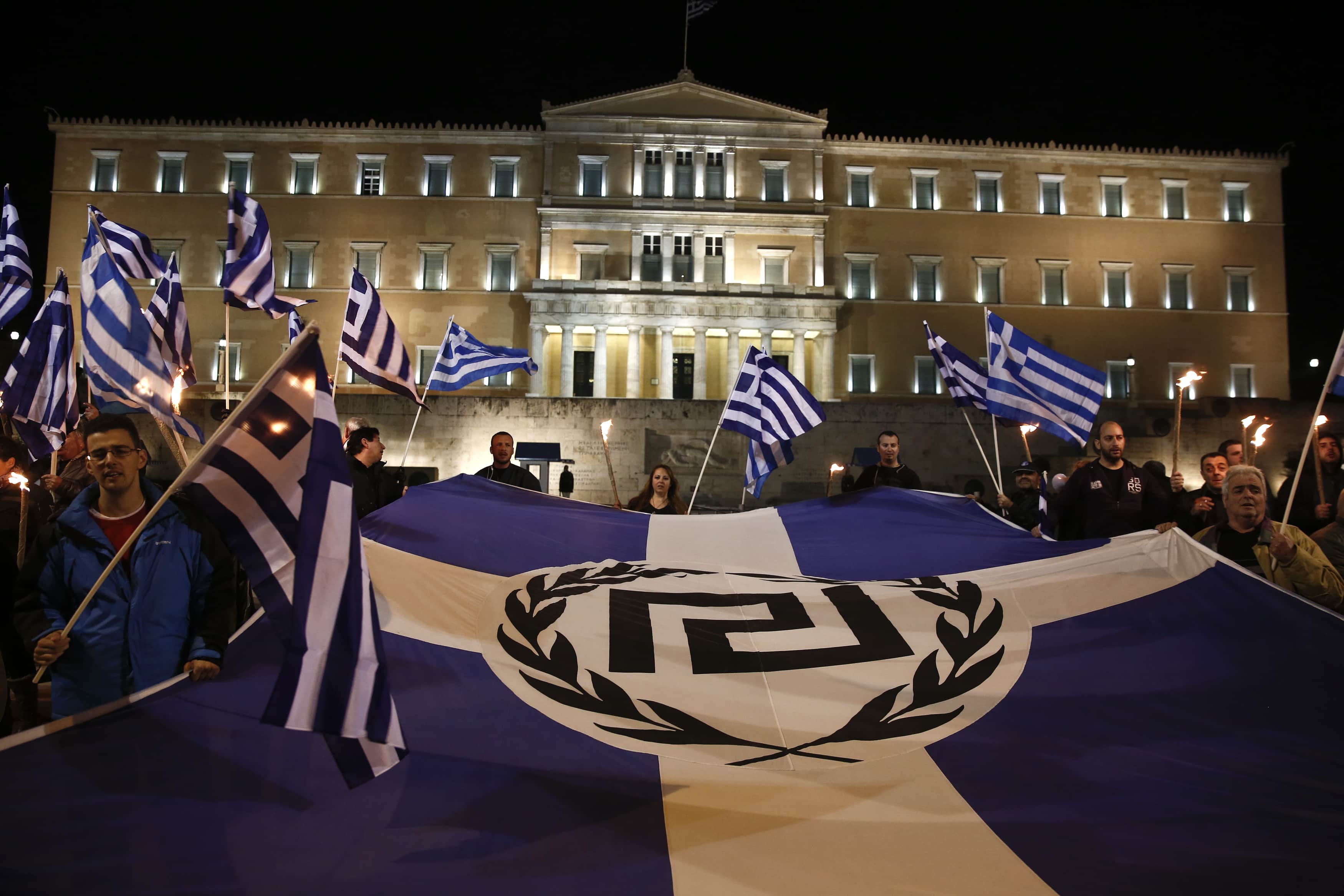 Supporters of Greece's far-right Golden Dawn party protest around a flag during a rally at central Syntagma square in Athens, 30 November 2013. , REUTERS/Yorgos Karahalis