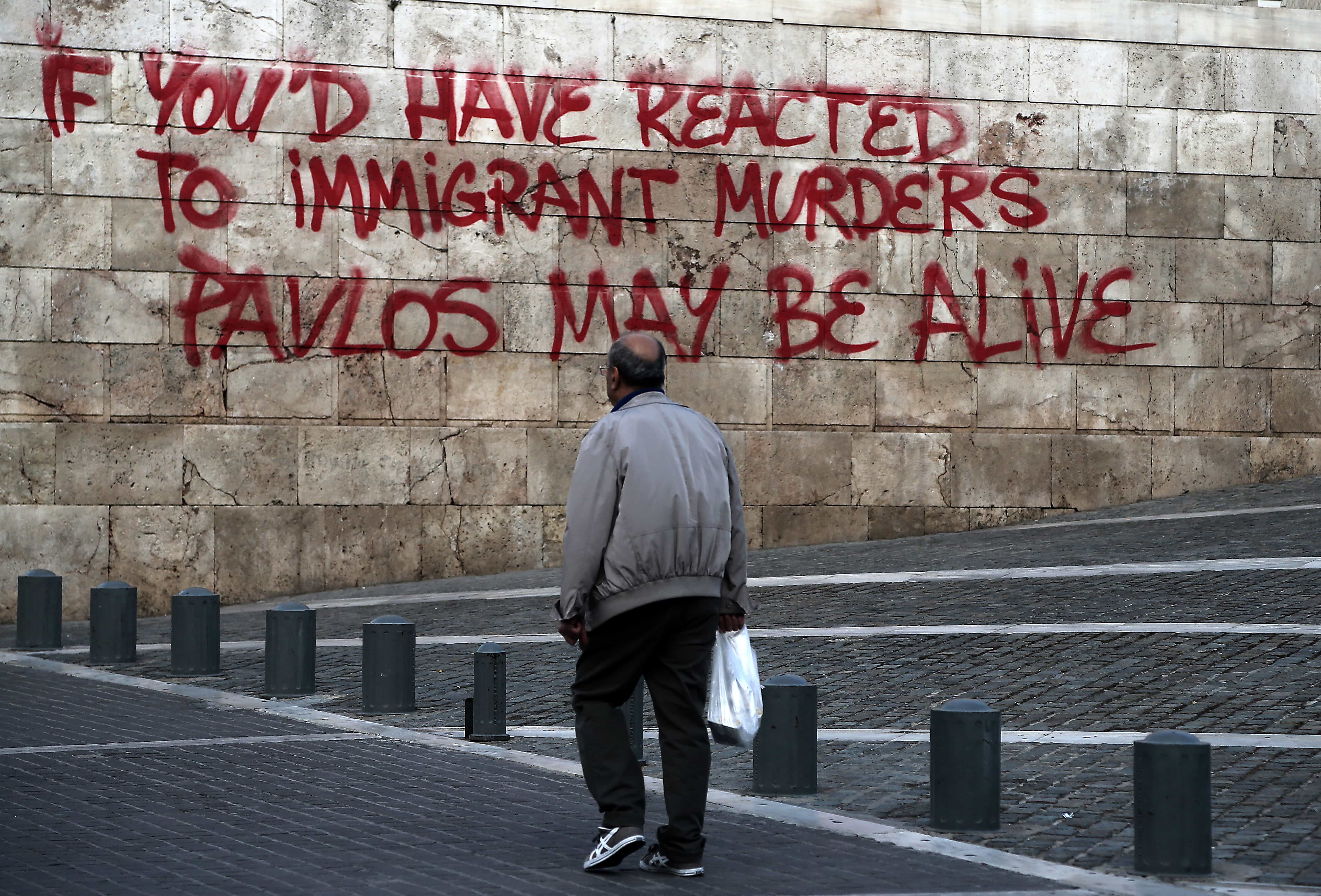 A man walks past a graffiti painted on the wall of the Athens' Academy referring to the recent murder of rapper Pavlos Fyssas, allegedly by a member of the far right Golden Dawn party, on 3 October 2013., AP Photo/Dimitri Messinis