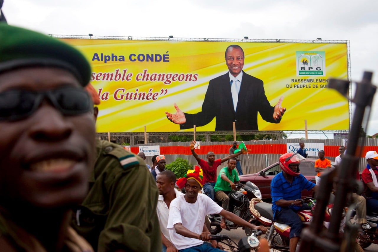 A gendarme stands near a poster of Guinea's presidential candidate Alpha Condé at a rally in Conakry, 19 October 2010, REUTERS/Stringer