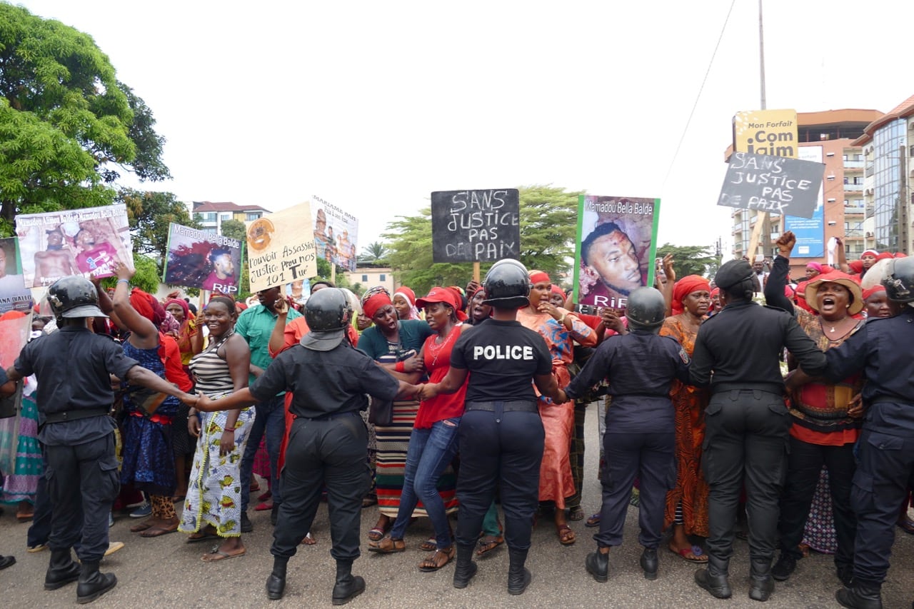 Police form a cordon as opposition supporters hold placards depicting youths who were killed during opposition protests, in Conakry, Guinea, 13 November 2018, CELLOU BINANI/AFP/Getty Images