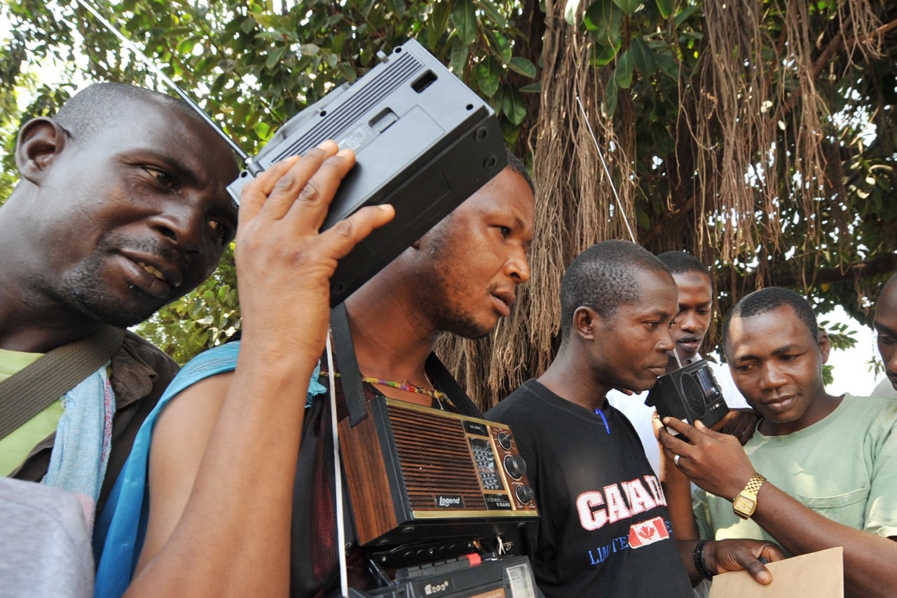 Young Guinean men listen to the radio in Kindia, 16 December 2009 , SIA KAMBOU/AFP/Getty Images