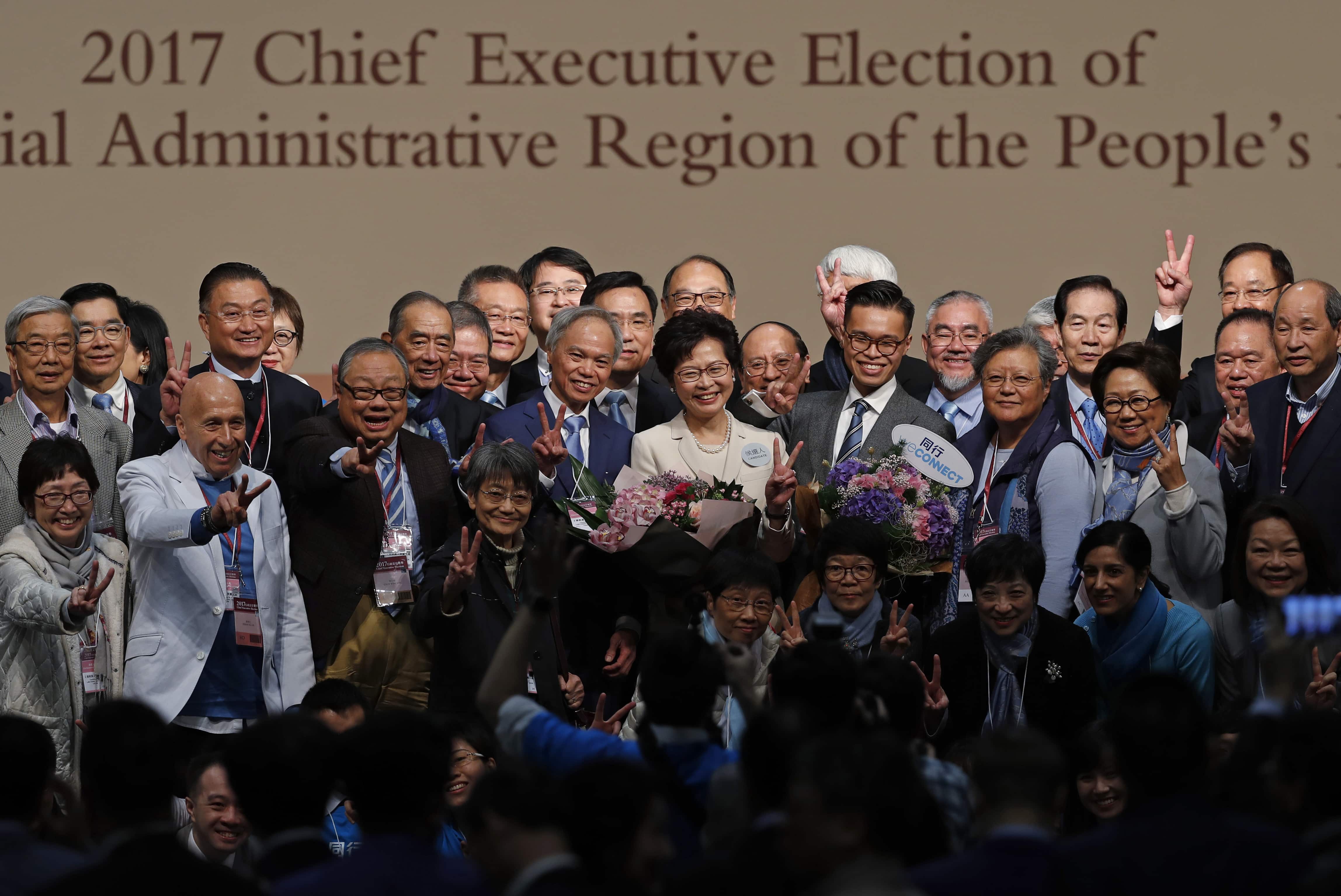 Former Hong Kong Chief Secretary Carrie Lam, center, smiles as she is congratulated by her supporters after winning the chief executive election in Hong Kong, 26 March 2017, AP Photo/Kin Cheung