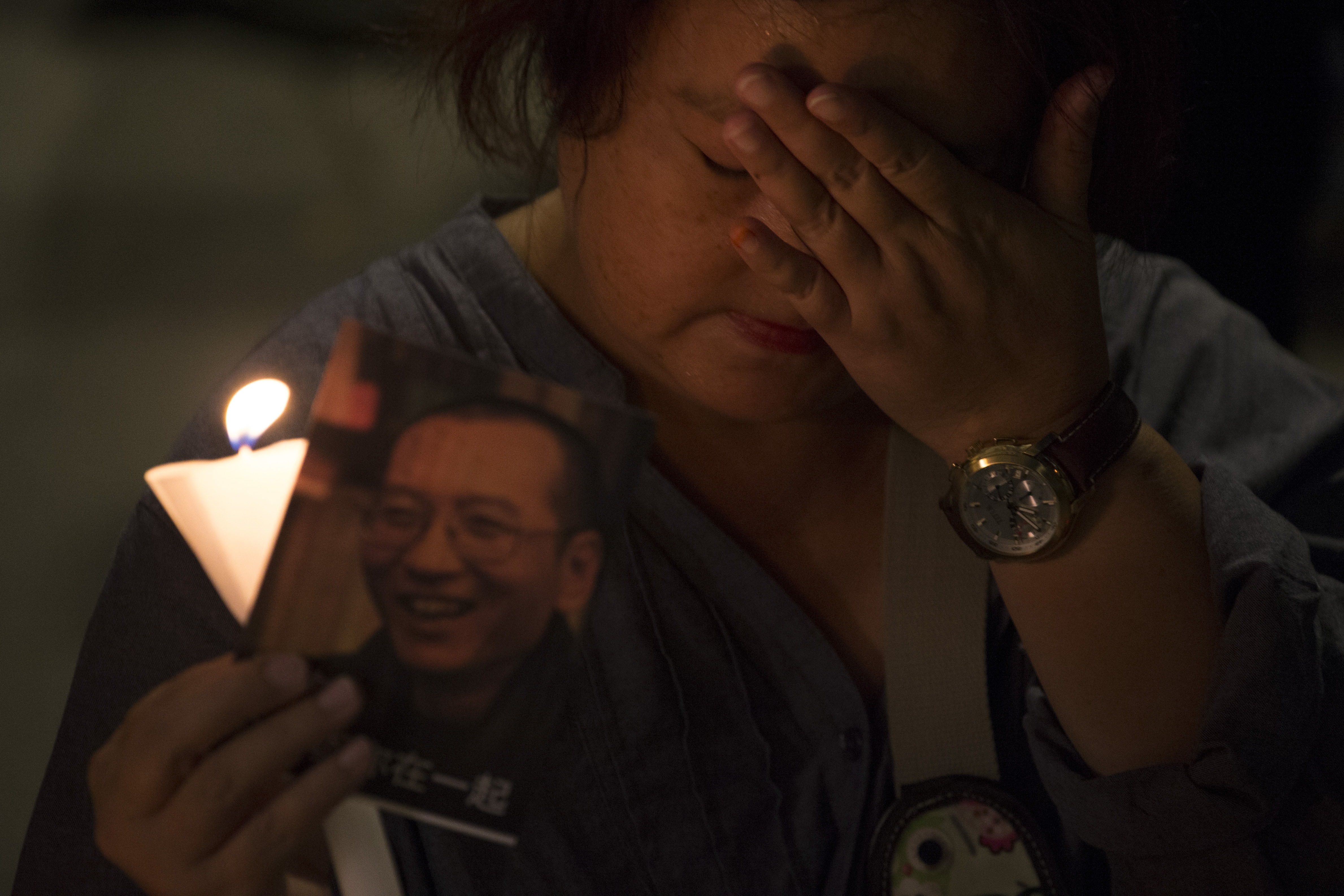 A supporter of Chinese Nobel Peace laureate Liu Xiaobo holds a candle and a picture of him as she joins others calling for his release in Hong Kong, 29 June 2017, AP Photo/Ng Han Guan