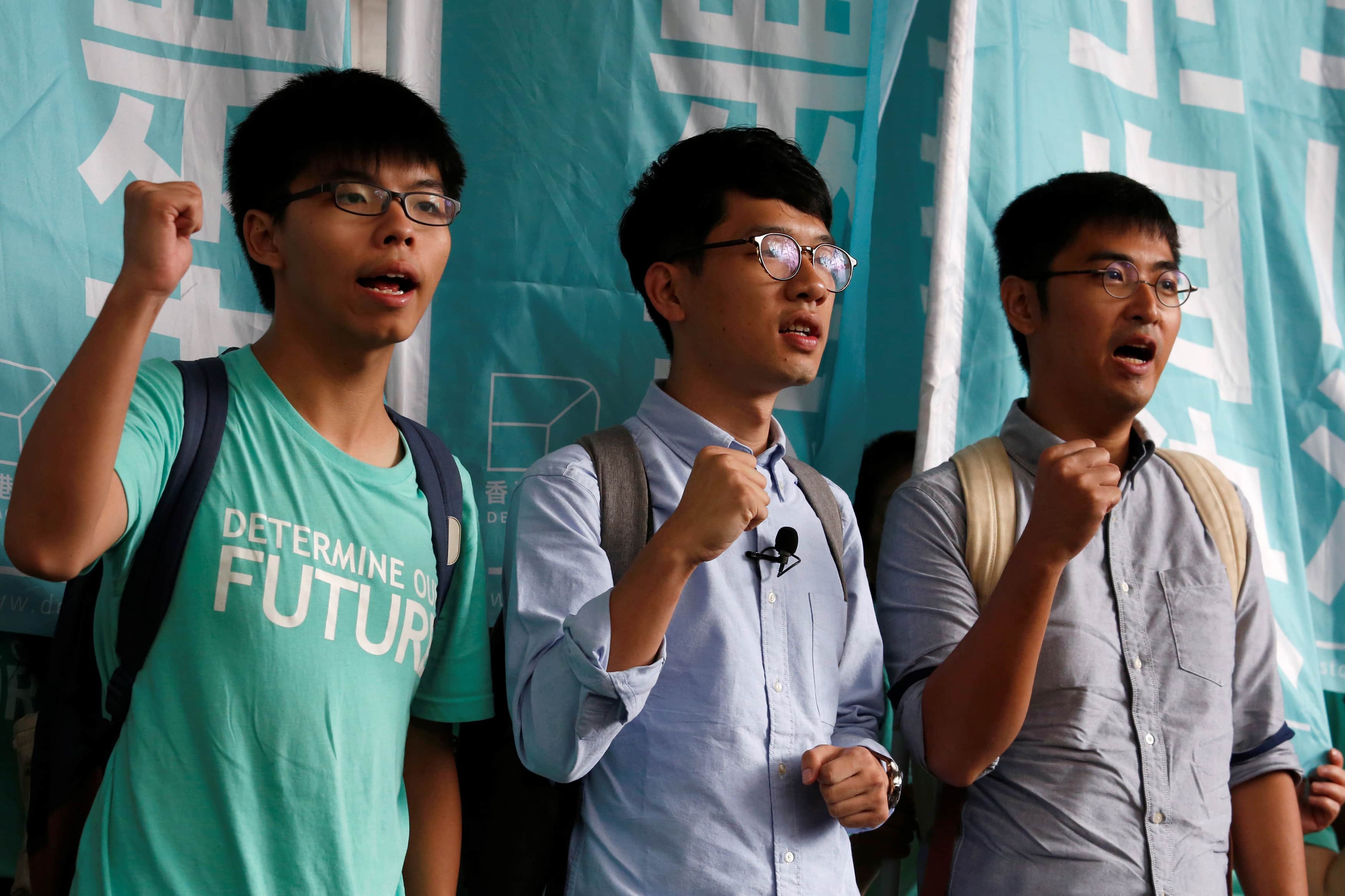 Student leaders Joshua Wong, Nathan Law and Alex Chow chant slogans before a verdict, on charges of inciting and participating in an illegal assembly in 2014, REUTERS/Bobby Yip
