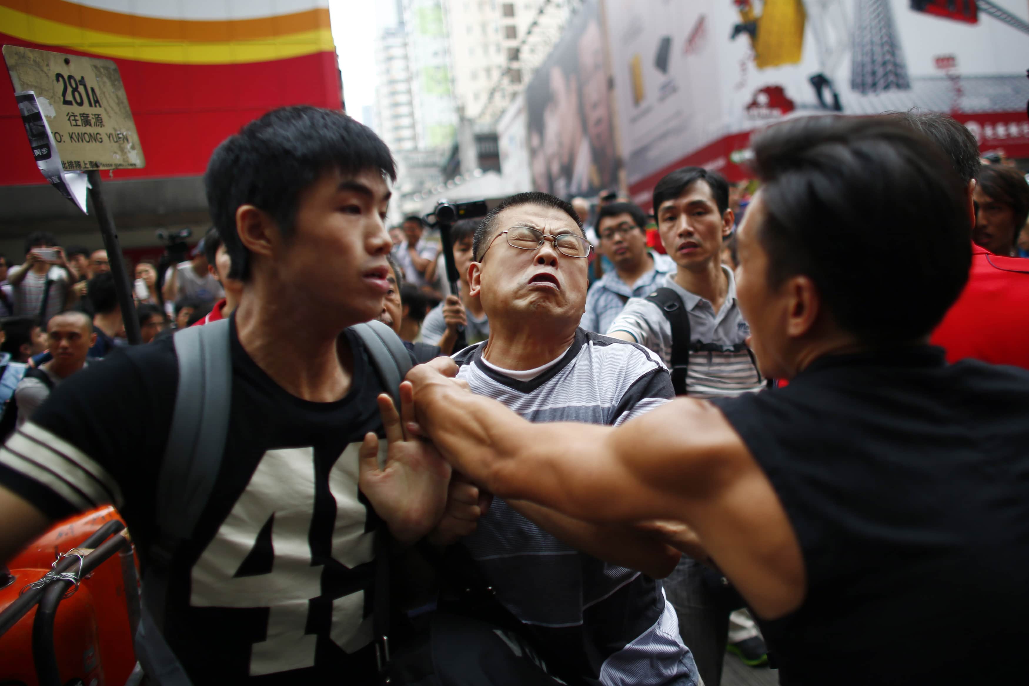 An anti-Occupy Central protester (C) scuffles with pro-democracy protesters as he tries to remove a barricade at a main street at Hong Kong's Mongkok shopping district, 4 October 2014, REUTERS/Carlos Barria