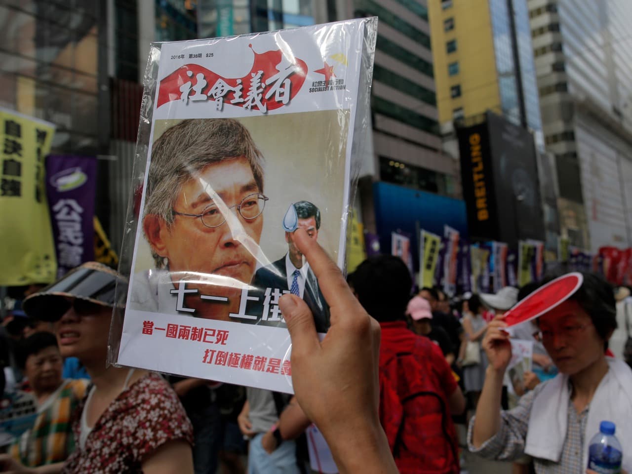 A protester raises a booklet with a picture of bookseller Lam Wing-kee on the cover during an annual pro-democracy protest in Hong Kong, 1 July 2016, AP Photo/Vincent Yu