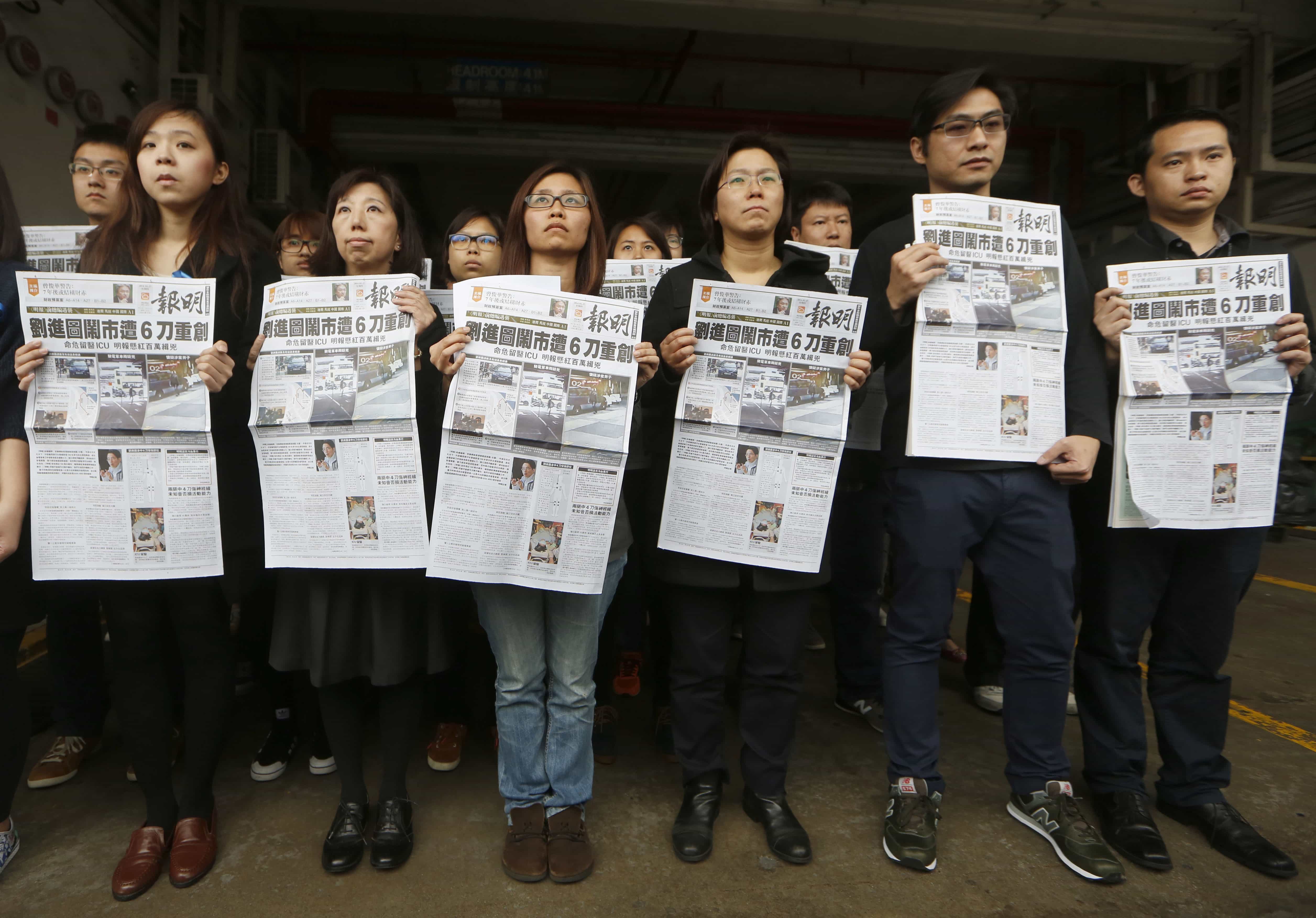 Editorial staff members of "Ming Pao" newspaper hold the front page of their newspaper with the headline on attack on former editor Kevin Lau during a protest outside the paper's office in Hong Kong, 27 February 2014, AP Photo/Kin Cheung