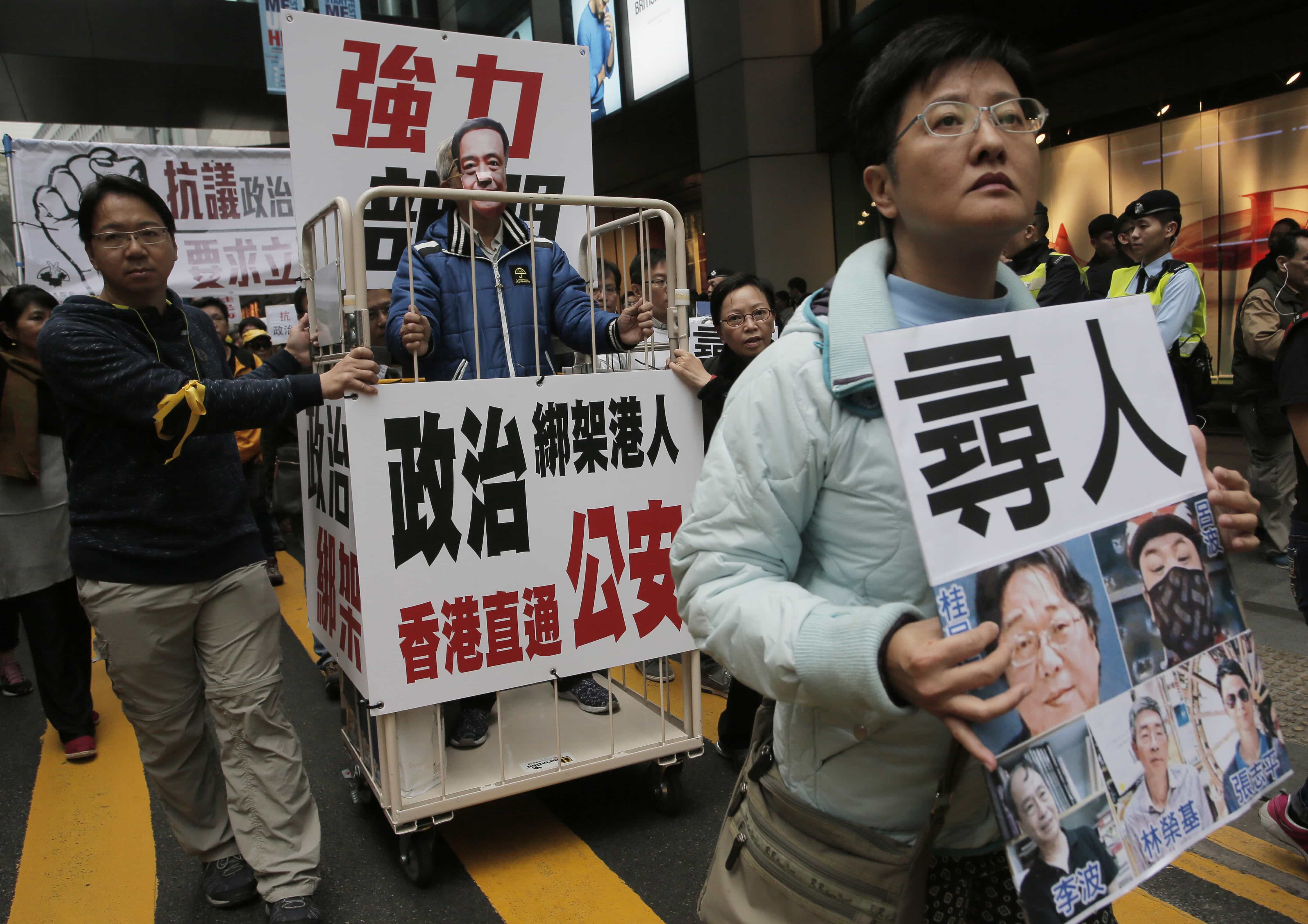 In this 10 January 2016 file photo, a protester wearing a mask of missing bookseller Lee Bo stands in a cage during a protest against the disappearances of booksellers in Hong Kong, AP Photo/Vincent Yu, File