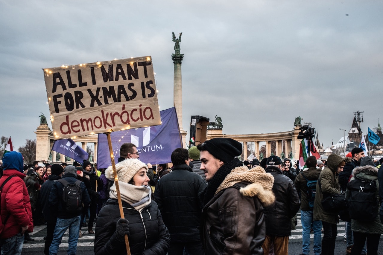 A woman holds a sign that reads, 'All I Want For Christmas Is Democracy' as thousands of protesters march against Hungary's labour laws, in Budapest, 16 December 2018, Martyn Aim/Getty Images