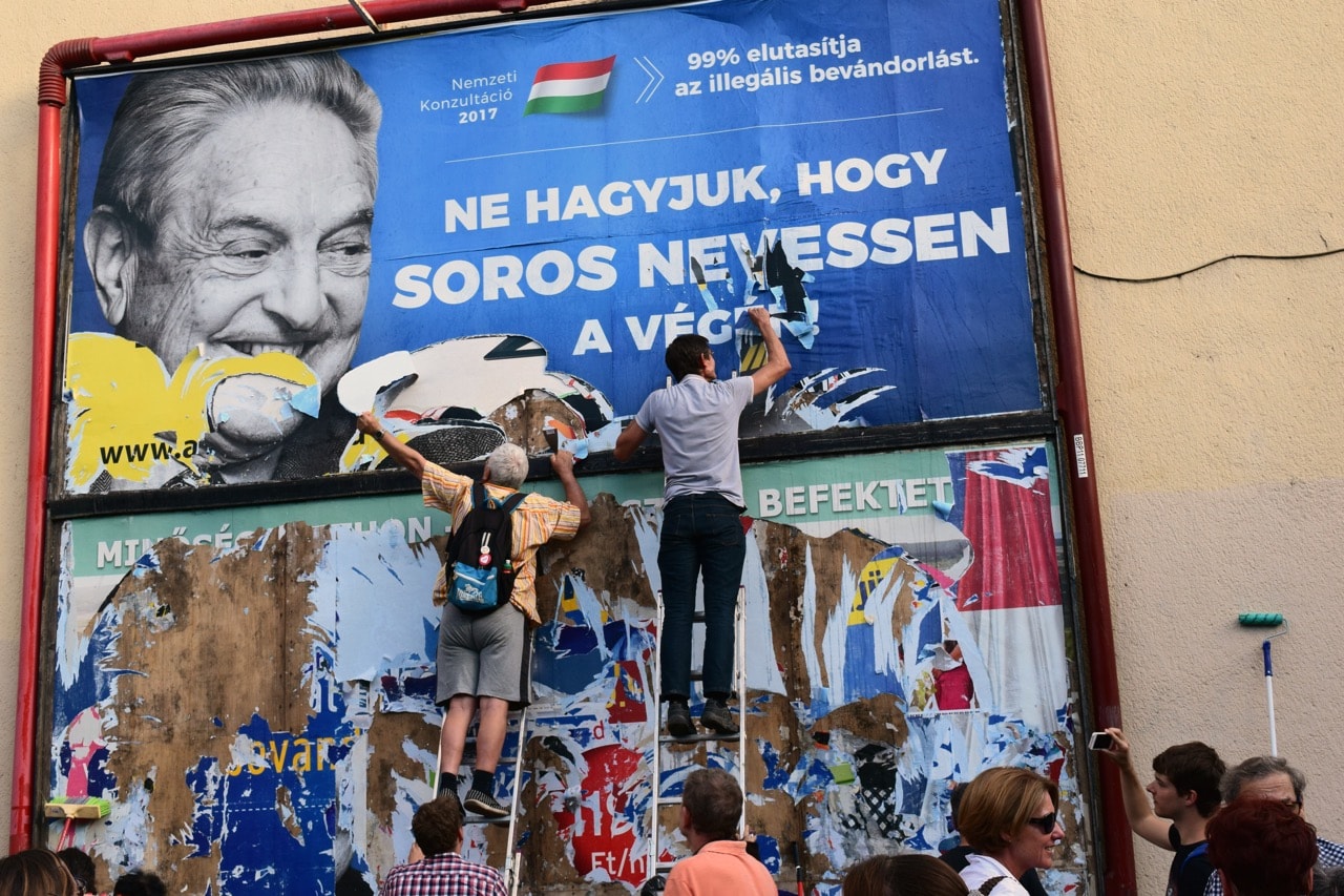 Activists from the Egyutt (Together) party tear down an ad by the Hungarian government against billionaire George Soros, in Budapest, 12 July 2017, AP Photo/Pablo Gorondi