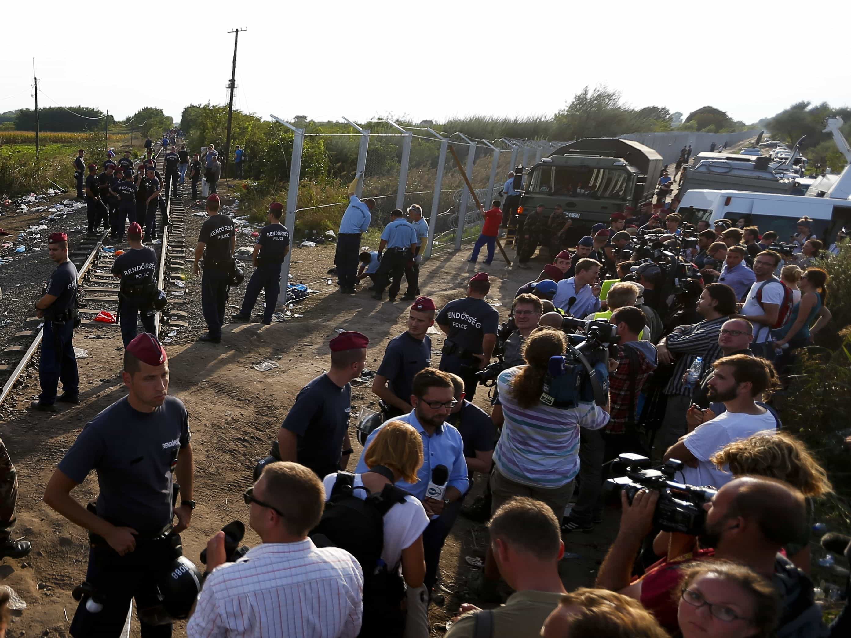Journalists watch as Hungarian police officers seal off the border with Serbia, near the Hungarian migrant collection point in Roszke, Hungary, 14 September 14 2015, REUTERS/Laszlo Balogh