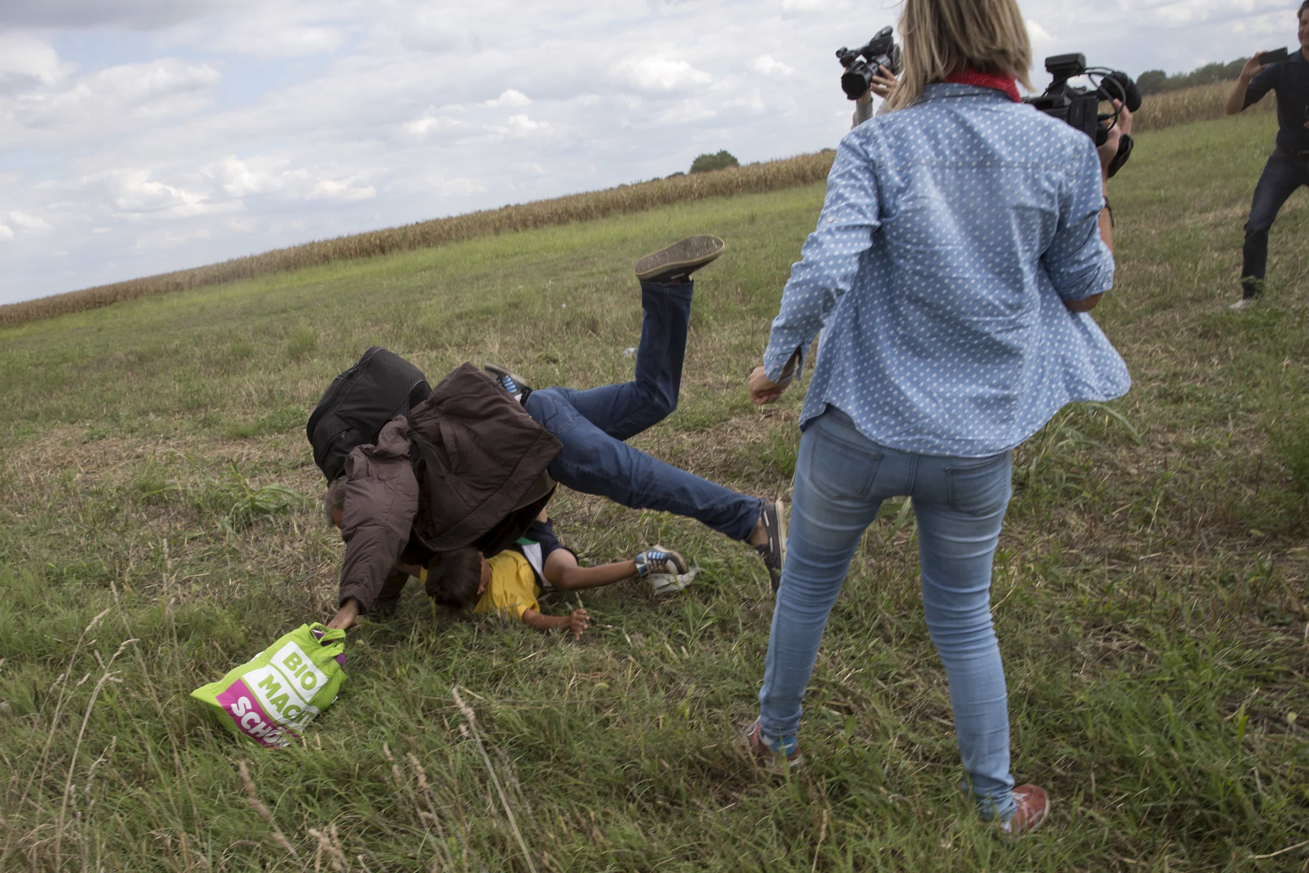 A migrant carrying a child falls after TV camerawoman Petra Laszlo trips him in Roszke village, Hungary, 8 September 2015, REUTERS/Marko Djurica