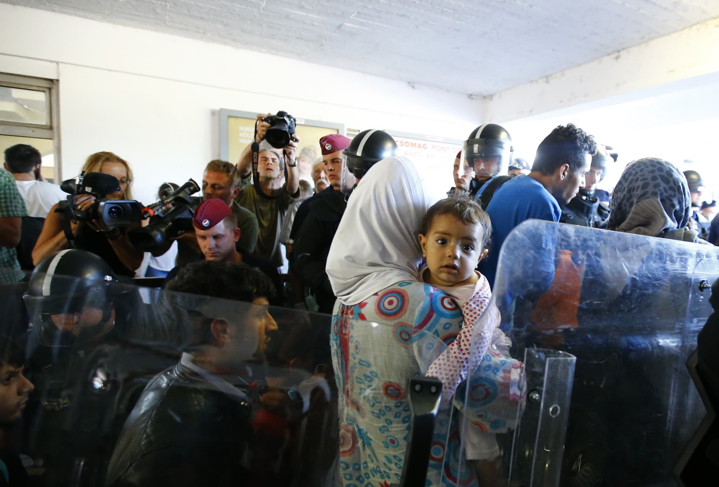 Migrants walk through a line of police after they left a train at Bicske railway station, Hungary, 4 September 2015, REUTERS/Leonhard Foeger