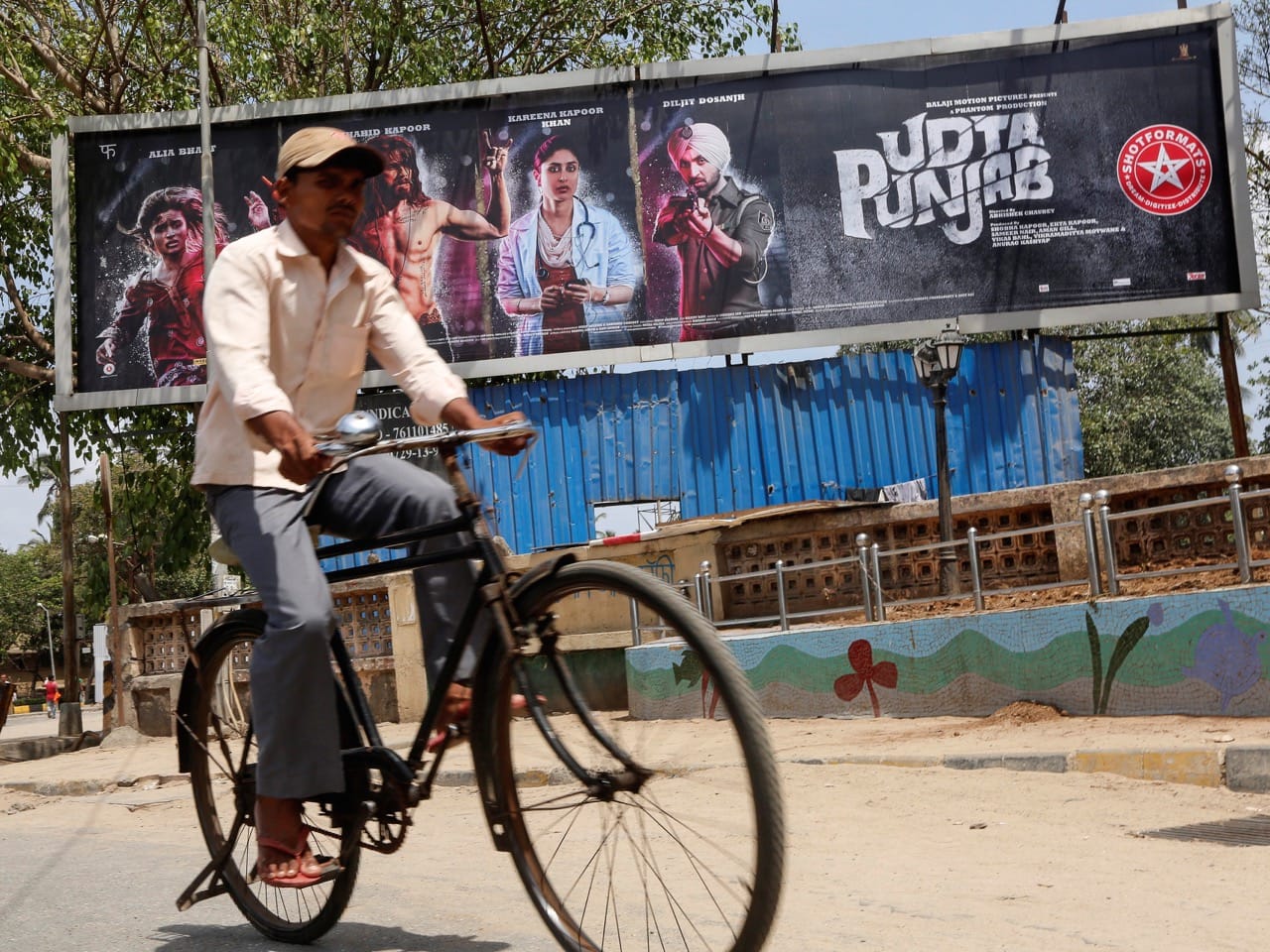 A man rides his bicycle past a poster of the movie "Udta Punjab" in Mumbai, India, 13 June 2016; it was released after a decision by the film censor board was challenged in court, REUTERS/Shailesh Andrade