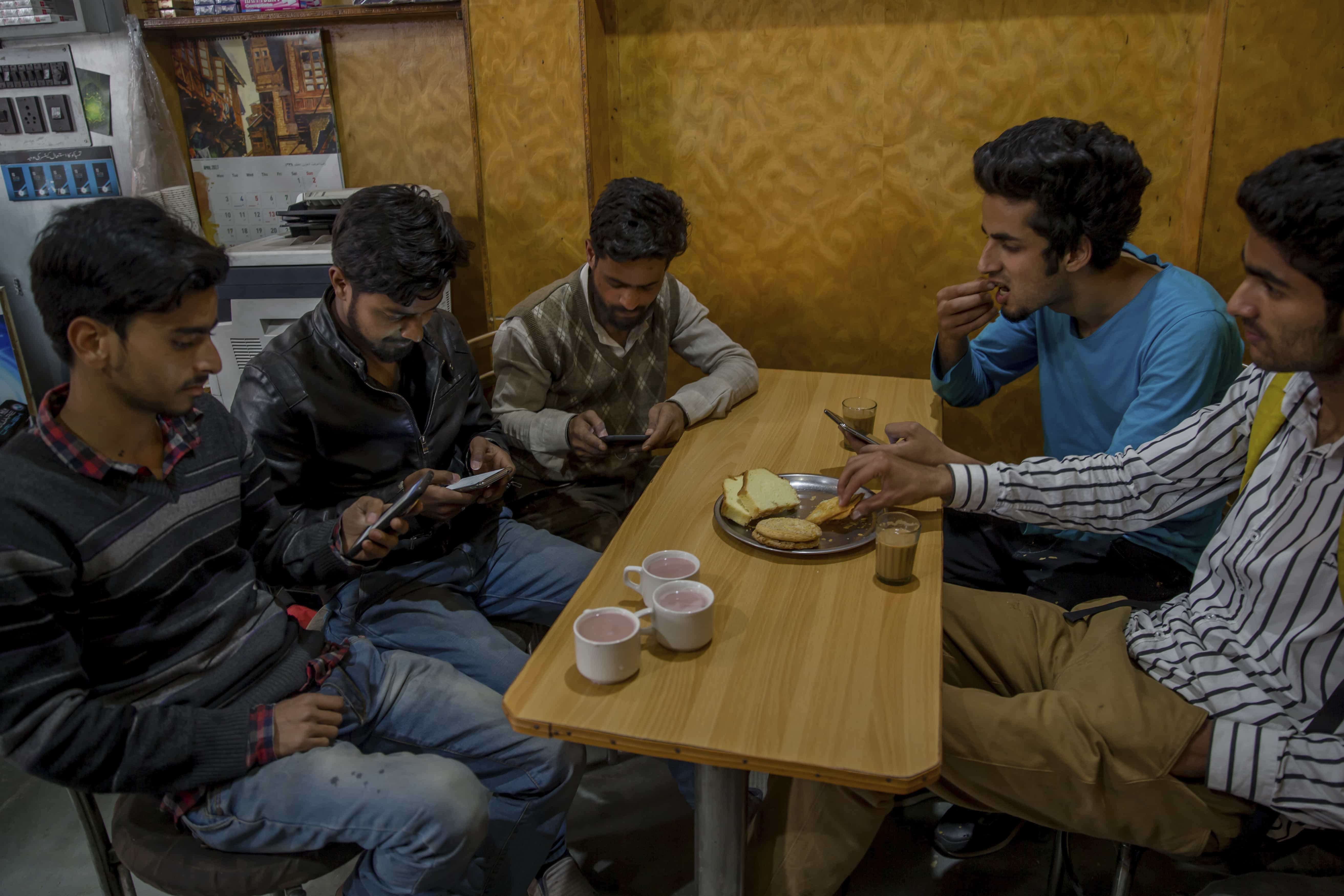 Kashmiri students browse the Internet on their mobile phones inside a restaurant in Srinagar, Kashmir, 26 April 2017, AP Photo/Dar Yasin