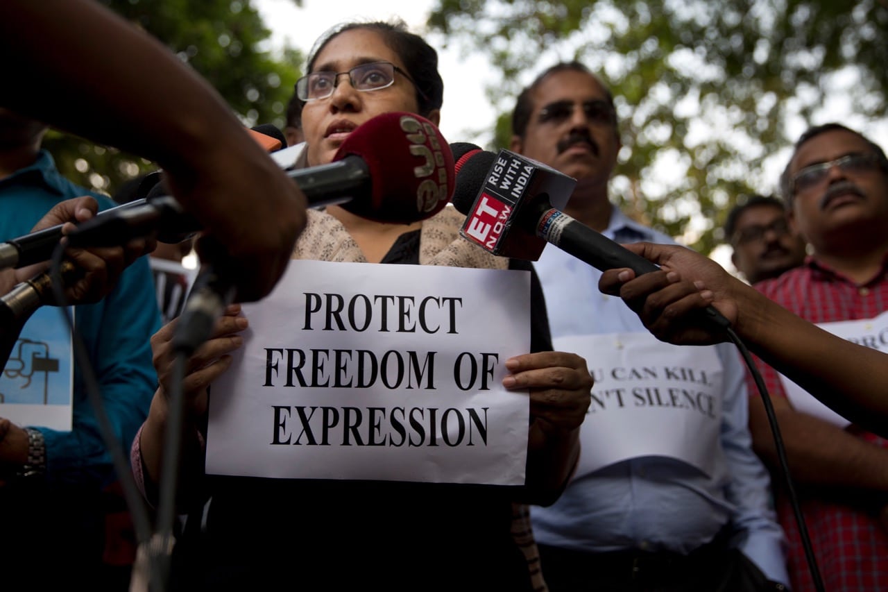 A journalist holds a placard and speaks to the media during a protest against the killing of TV news reporter Shantanu Bhowmik, in New Delhi, India, 21 September 2017, AP Photo/Tsering Topgyal