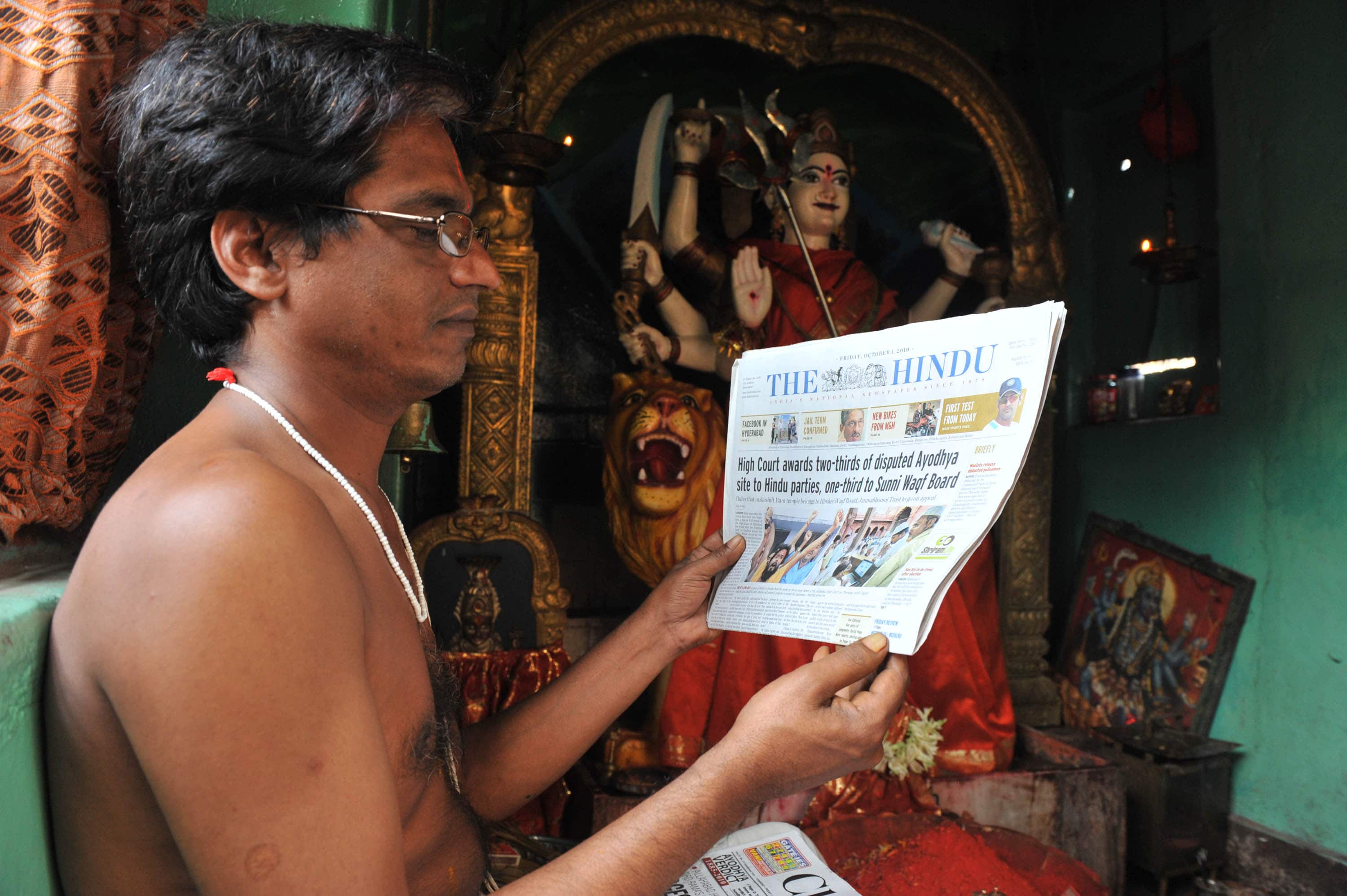 Indian Hindu priest reads a copy of "The Hindu" newspaper, in a Hyderabad temple, India, 1 October 2010, NOAH SEELAM/AFP/Getty Images