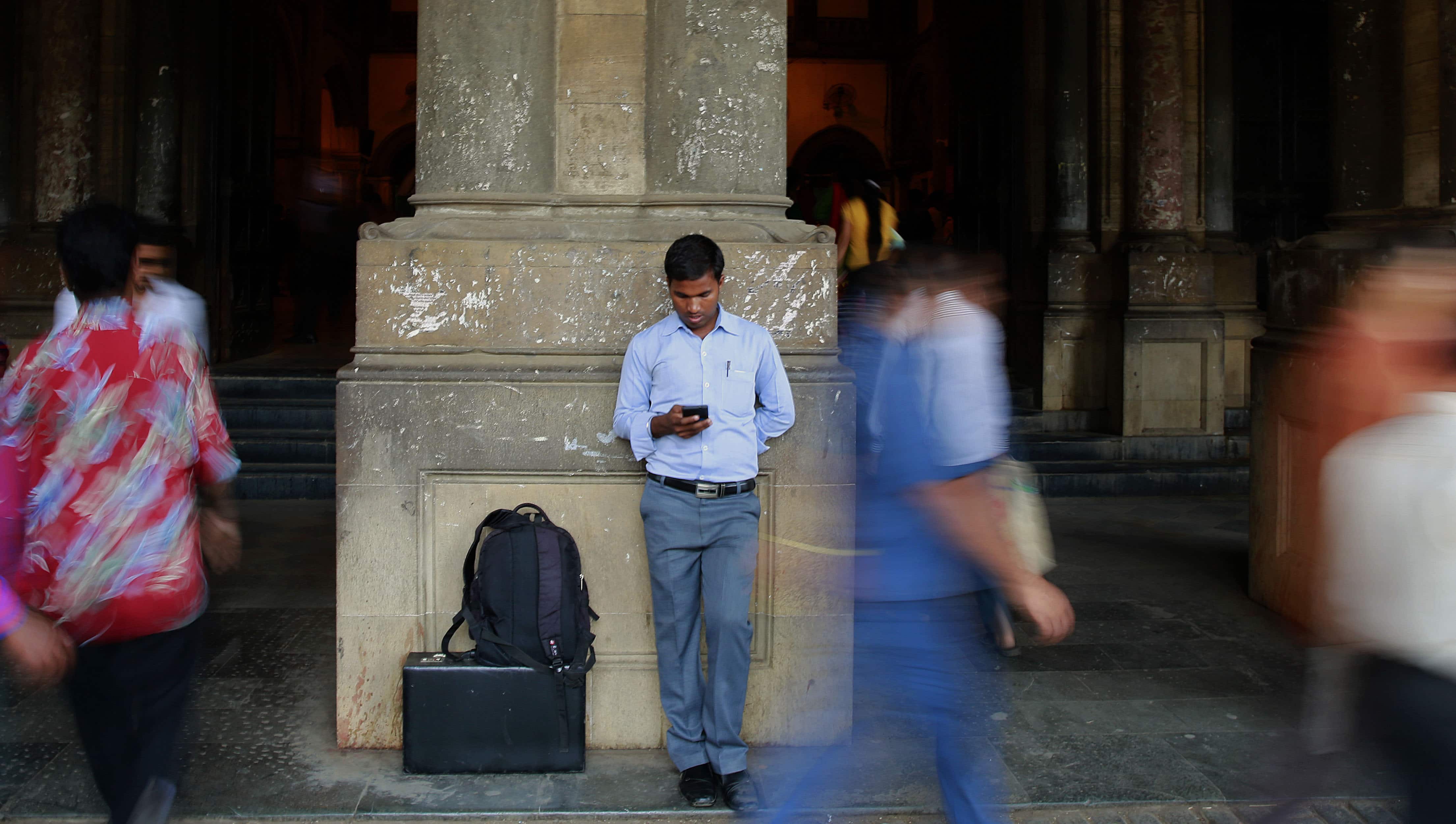 An Indian man surfs the internet on his smartphone outside a railway station in Mumbai on 24 March 2015, AP Photo/Rafiq Maqbool