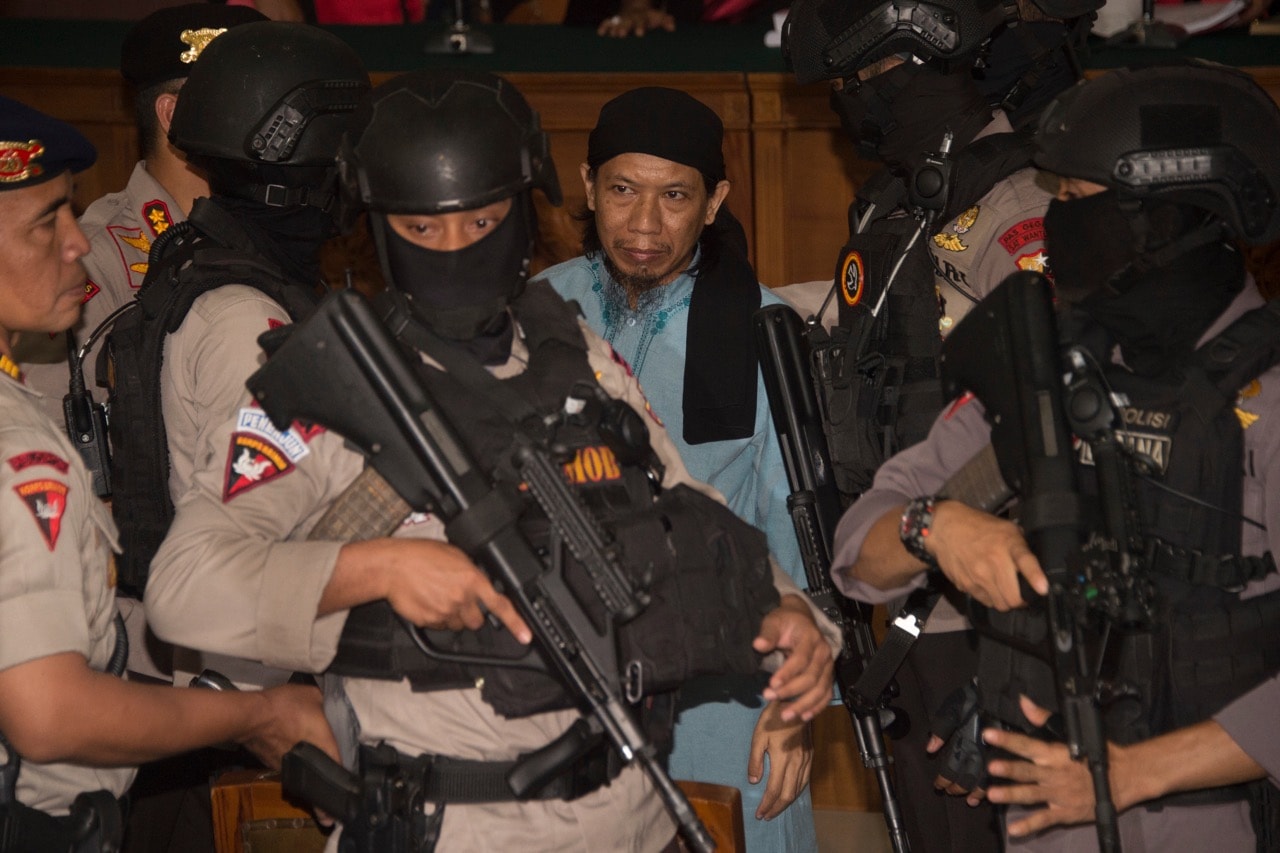 Indonesian anti-terror police officers escort an individual accused of masterminding an attack in the capital Jakarta, at a South Jakarta court, 22 June 2018, BAY ISMOYO/AFP/Getty Images