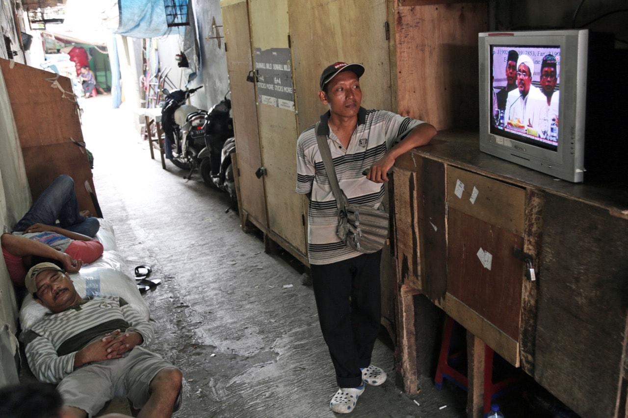 Workers watch a TV broadcast of a press conference by the leader of the Islamic Defenders Front, Rizieq Shihab, in Jakarta, Indonesia, 28 November 2016, AP Photo/Achmad Ibrahim