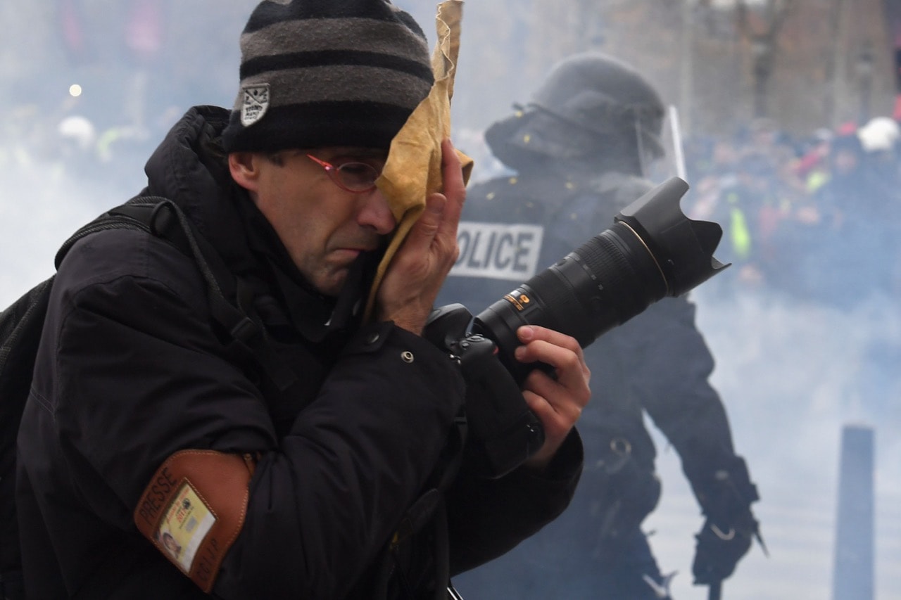 A journalist reacts to tear gas fired by the police during a "Yellow Vests" protest in Paris, France, 8 December 2018, ALAIN JOCARD/AFP/Getty Images