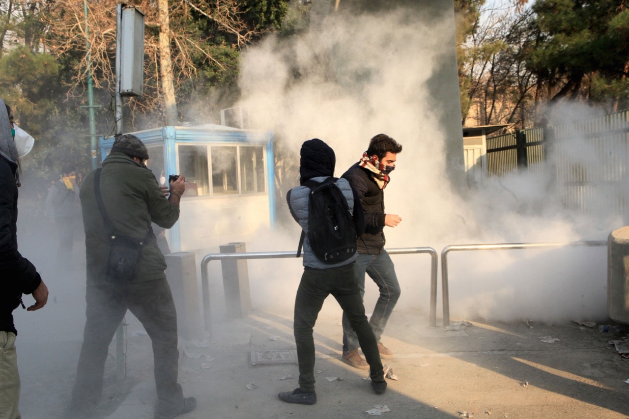 A man takes a photograph while students run for cover from tear gas at the University of Tehran during a demonstration in Tehran, Iran, 30 December 2017, STR/AFP/Getty Images