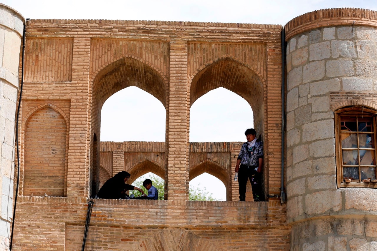 Iranians sit on the 33 Arches bridge over the Zayandeh Rud river in Isfahan, which now runs dry due to water extraction before it reaches the city, 11 April 2018, ATTA KENARE/AFP/Getty Images