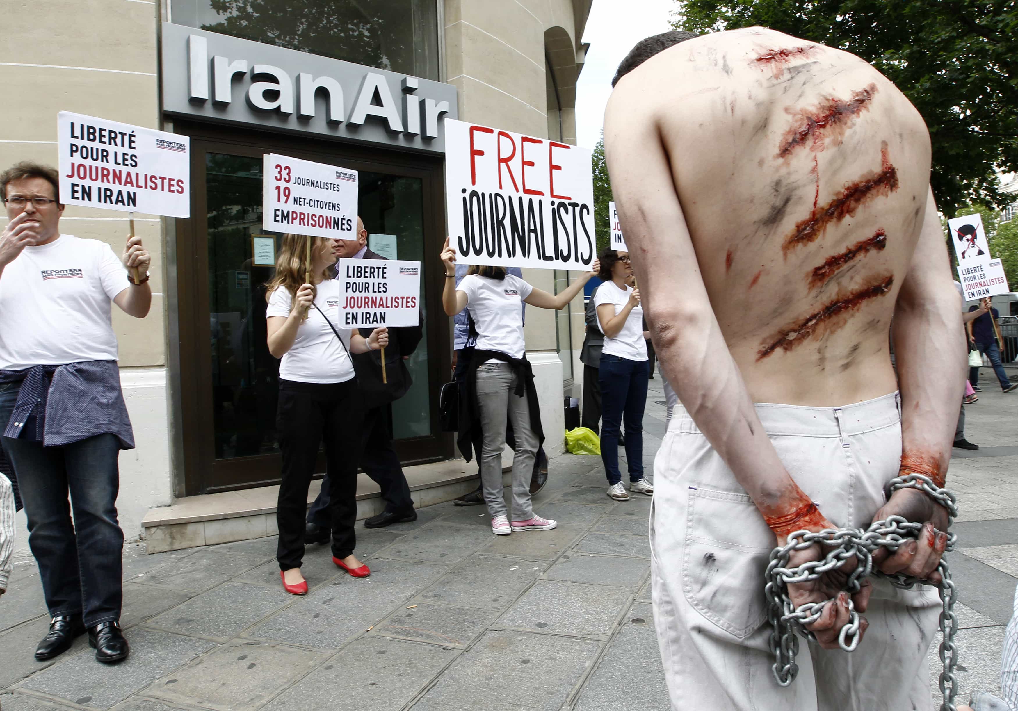 An activist from Reporters Without Borders (RSF) with fake injuries and chains attends a demonstration in front of the Iran Air airline company in Paris in 2012 to condemn the imprisonment of journalists in Iran, REUTERS/Jacky Naegelen