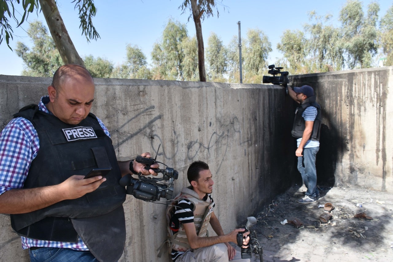 Video journalists take cover behind a wall amid fighting in the region of Altun Kupri, about 50 km from Erbil, the capital of autonomous Iraqi Kurdistan, 20 October 2017, MARWAN IBRAHIM/AFP/Getty Images