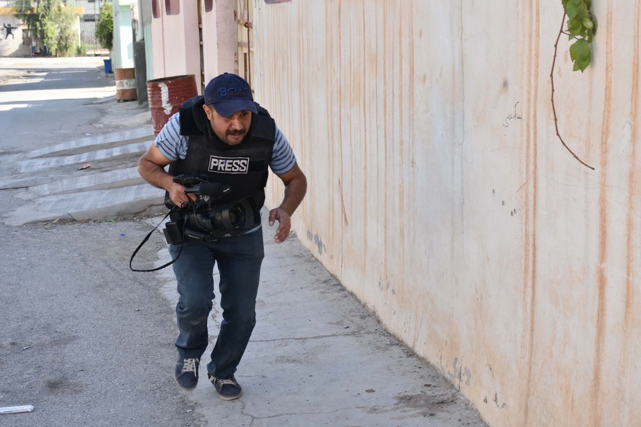 A video journalists runs while taking cover behind a wall amid fighting in the region of Altun Kupri, about 50 km from Arbil, the capital of autonomous Iraqi Kurdistan, 20 October 2017, MARWAN IBRAHIM/AFP/Getty Images