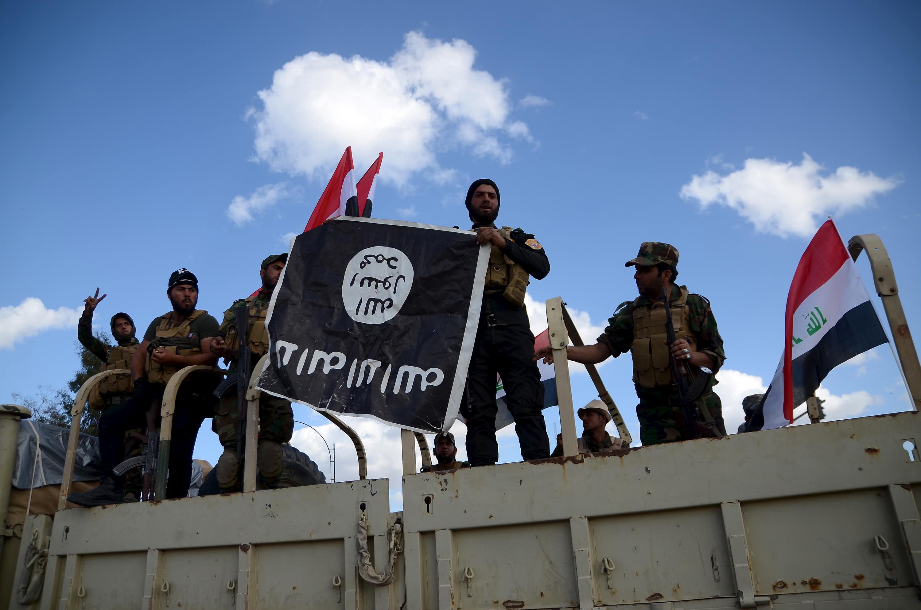 Shi'ite paramilitary fighters hold an Islamist State flag which they pulled down in Tikrit March 31, 2015, REUTERS/Stringer