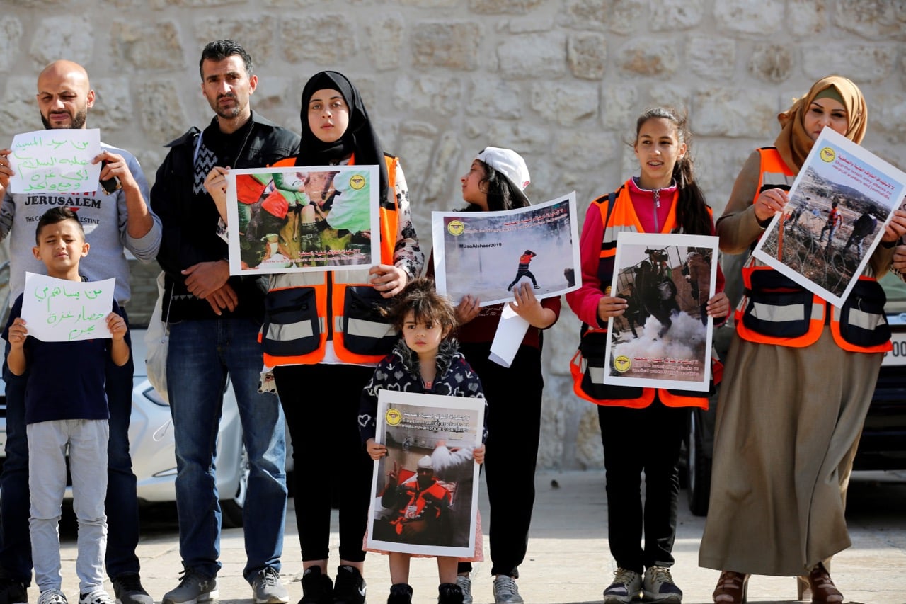 Palestinians hold placards in front of El Mehd Church during a protest after Israeli forces targeted Palestinian medical staff and journalists in Gaza, in Bethlehem, West Bank, 8 April 2018, Wisam Hashlamoun/Anadolu Agency/Getty Images