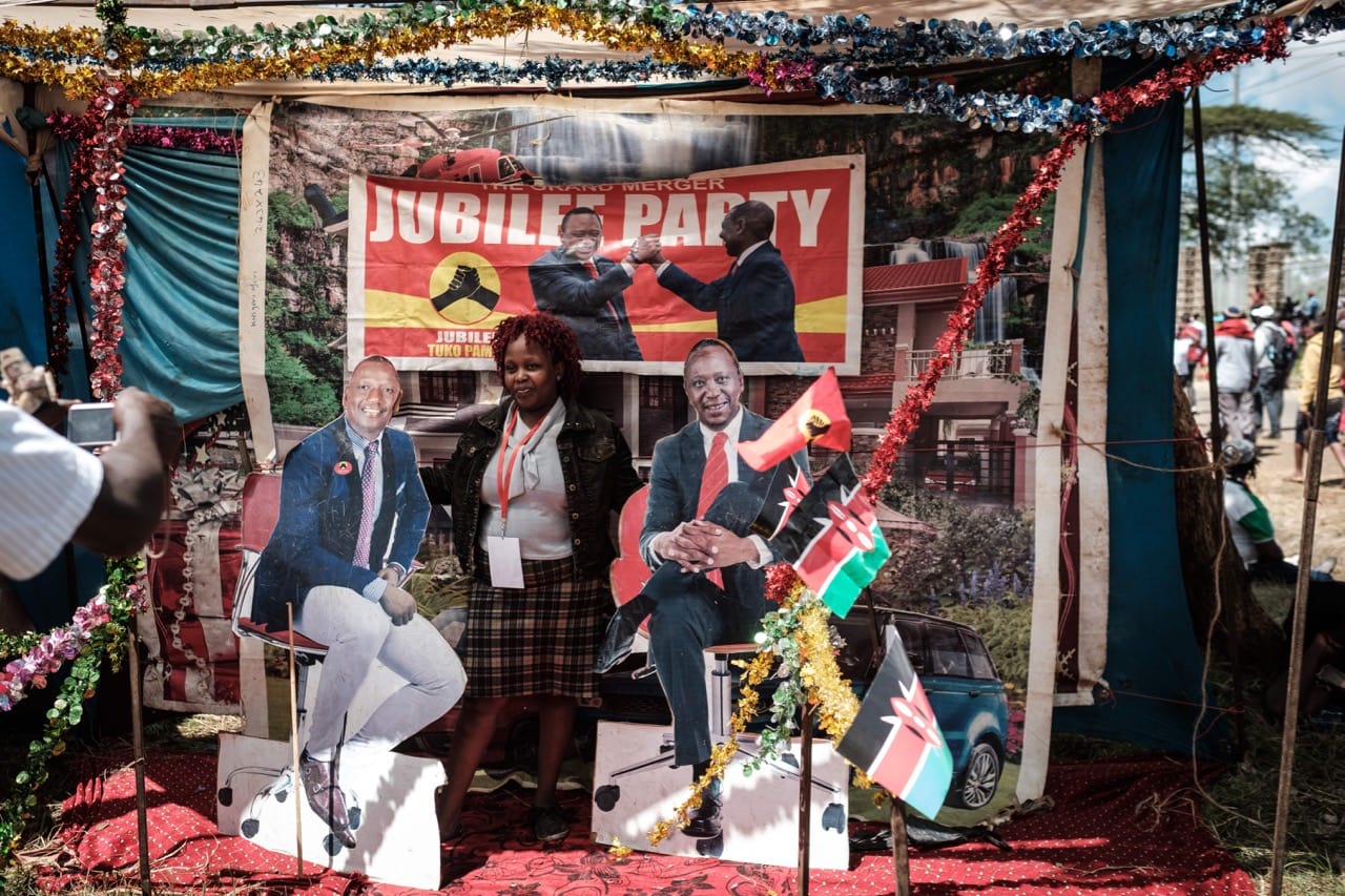 A woman poses for a photograph between posters of Kenya's President Uhuru Kenyatta and Vice-President William Ruto at a temporary photo studio during the re-elected President's inauguration ceremony in Nairobi, 28 November 2017, YASUYOSHI CHIBA/AFP/Getty Images