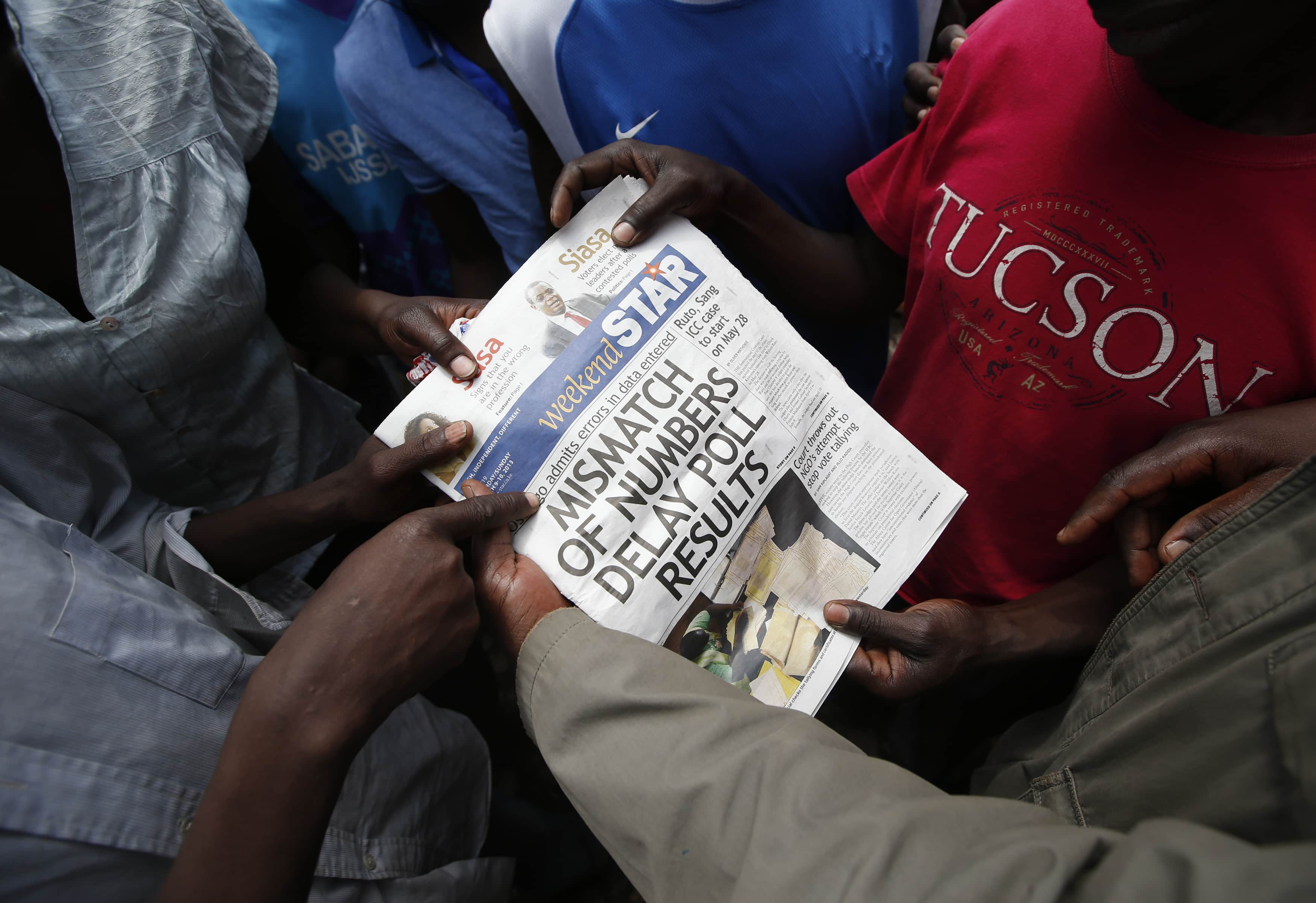 Supporters of Kenyan Prime Minister Raila Odinga look at a newspaper in the Mathare slum in Nairobi, 9 March 2013., REUTERS/Goran Tomasevic