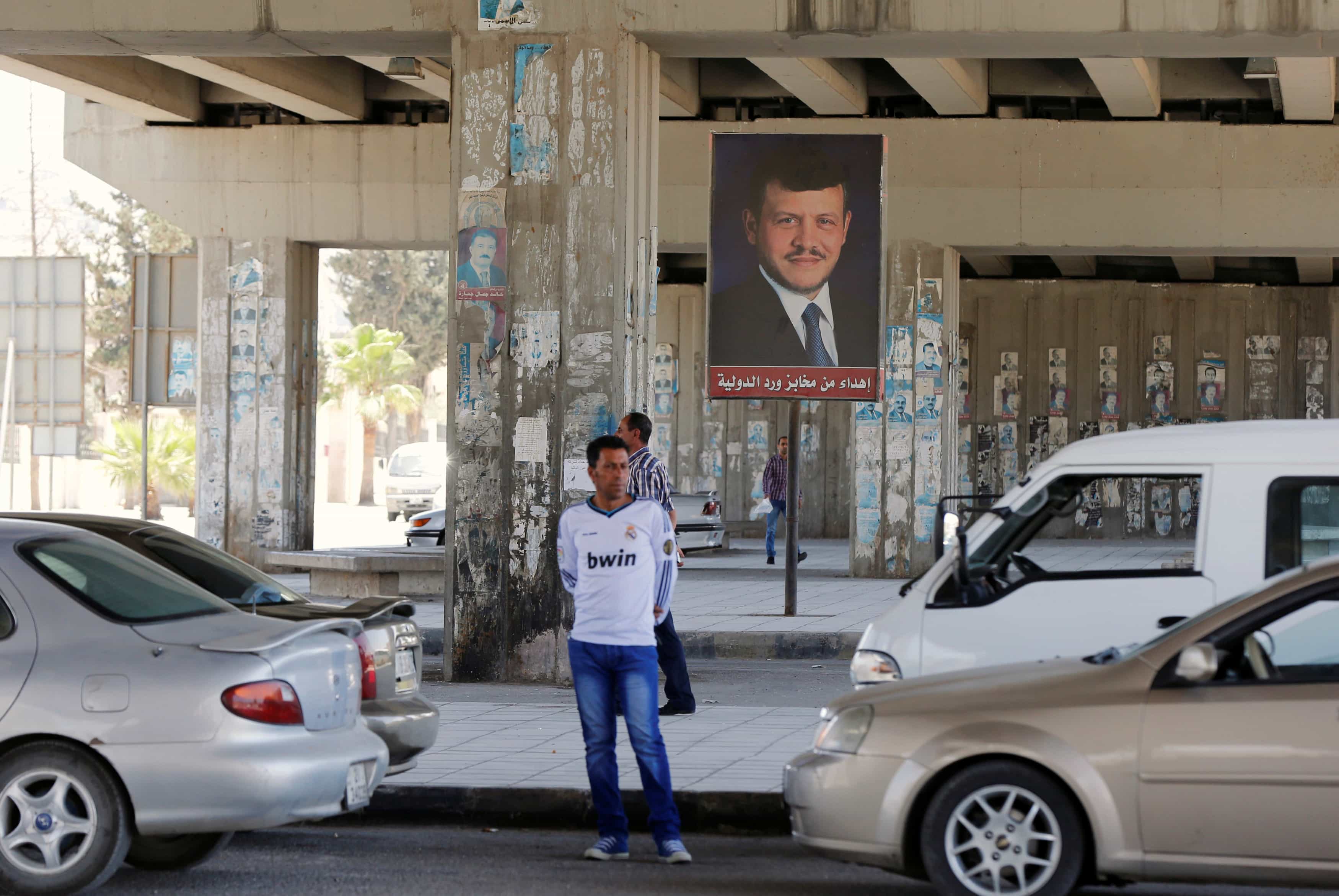 People walk past a poster of Jordan's King Abdullah near the General Intelligence directorate offices near al Baqaa Refugee Camp, north of Amman, Jordan, June 6, 2016, REUTERS/Muhammad Hamed