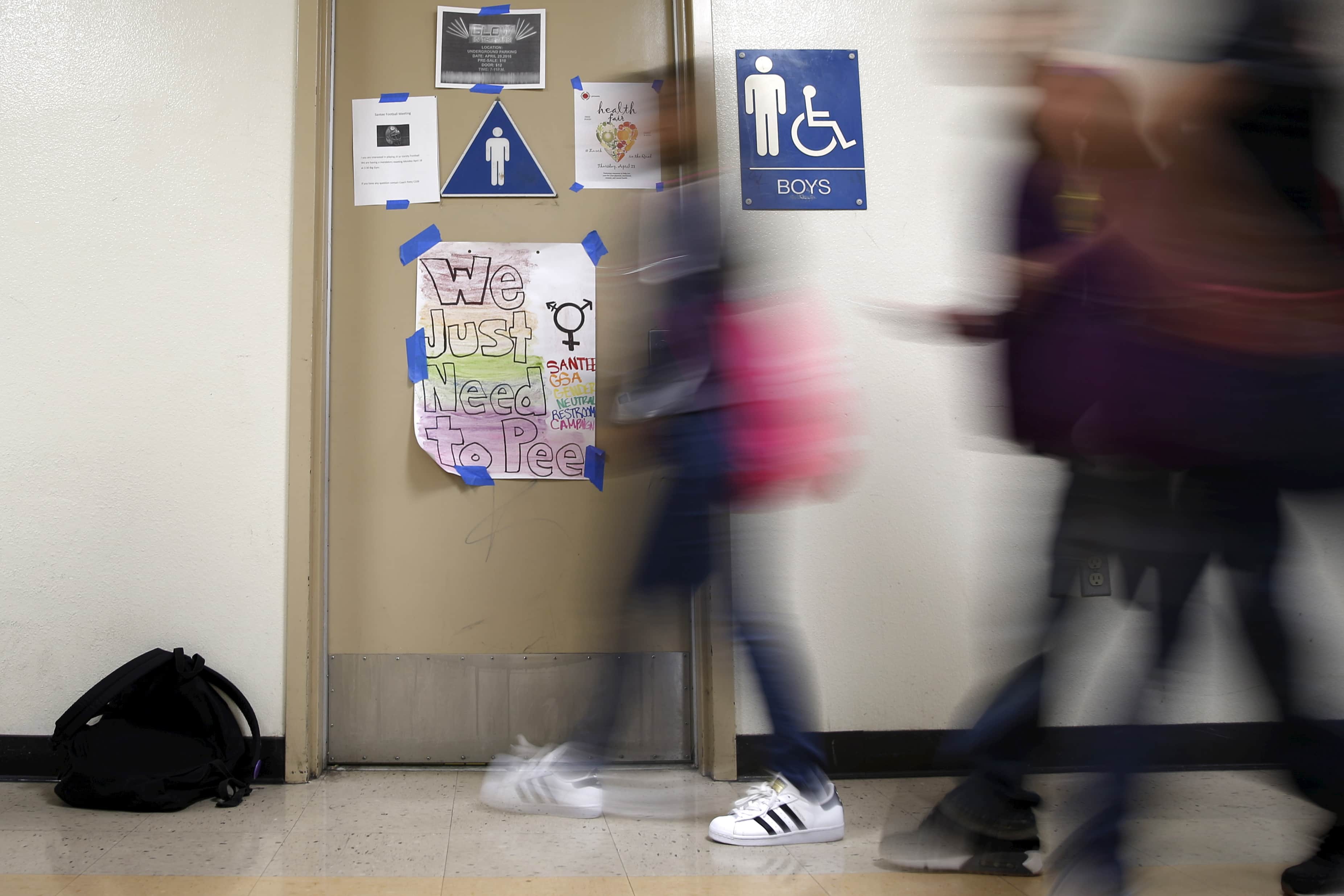 Students walk past a protest sign on a bathroom which helped lobby for the first gender-neutral restroom in the Los Angeles school district at Santee Education Complex high school in Los Angeles, California, 18 April 2016