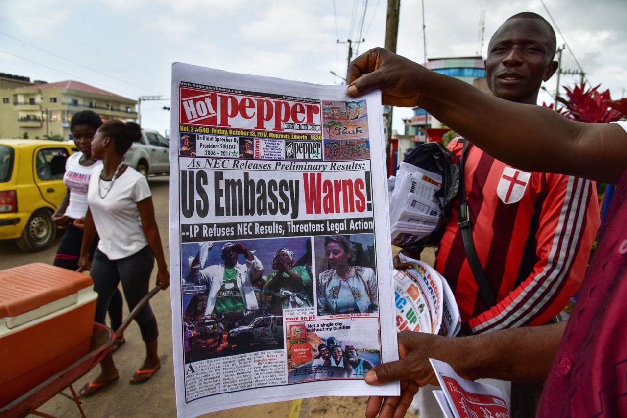 A man displays a copy of the "Hot Pepper" newspaper in a street in Monrovia, Liberia, 13 October 2017, ISSOUF SANOGO/AFP/Getty Images