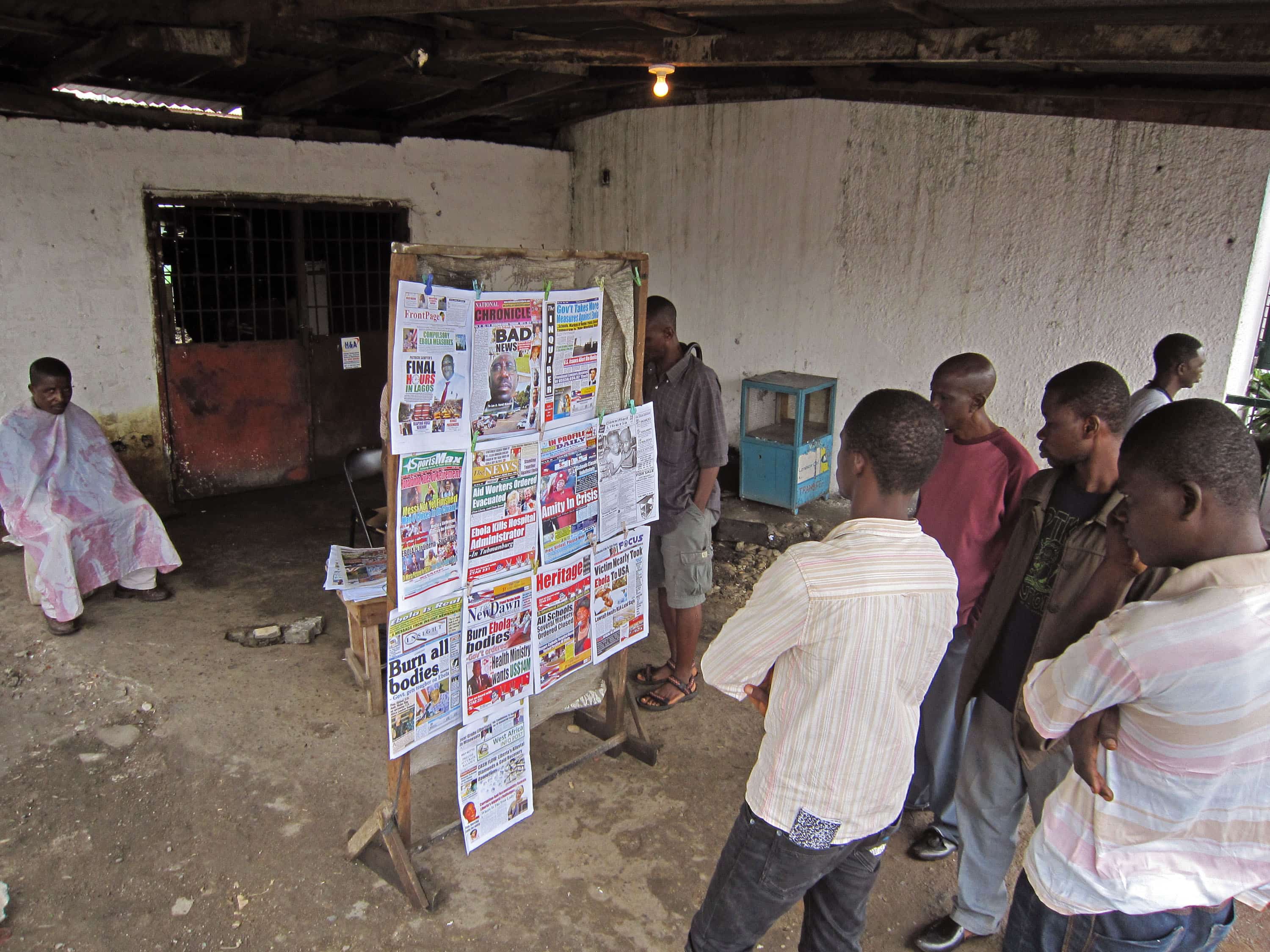People read local newspaper headlines in Monrovia, Liberia, 31 July 2014, AP Photo/Jonathan Paye-Layleh