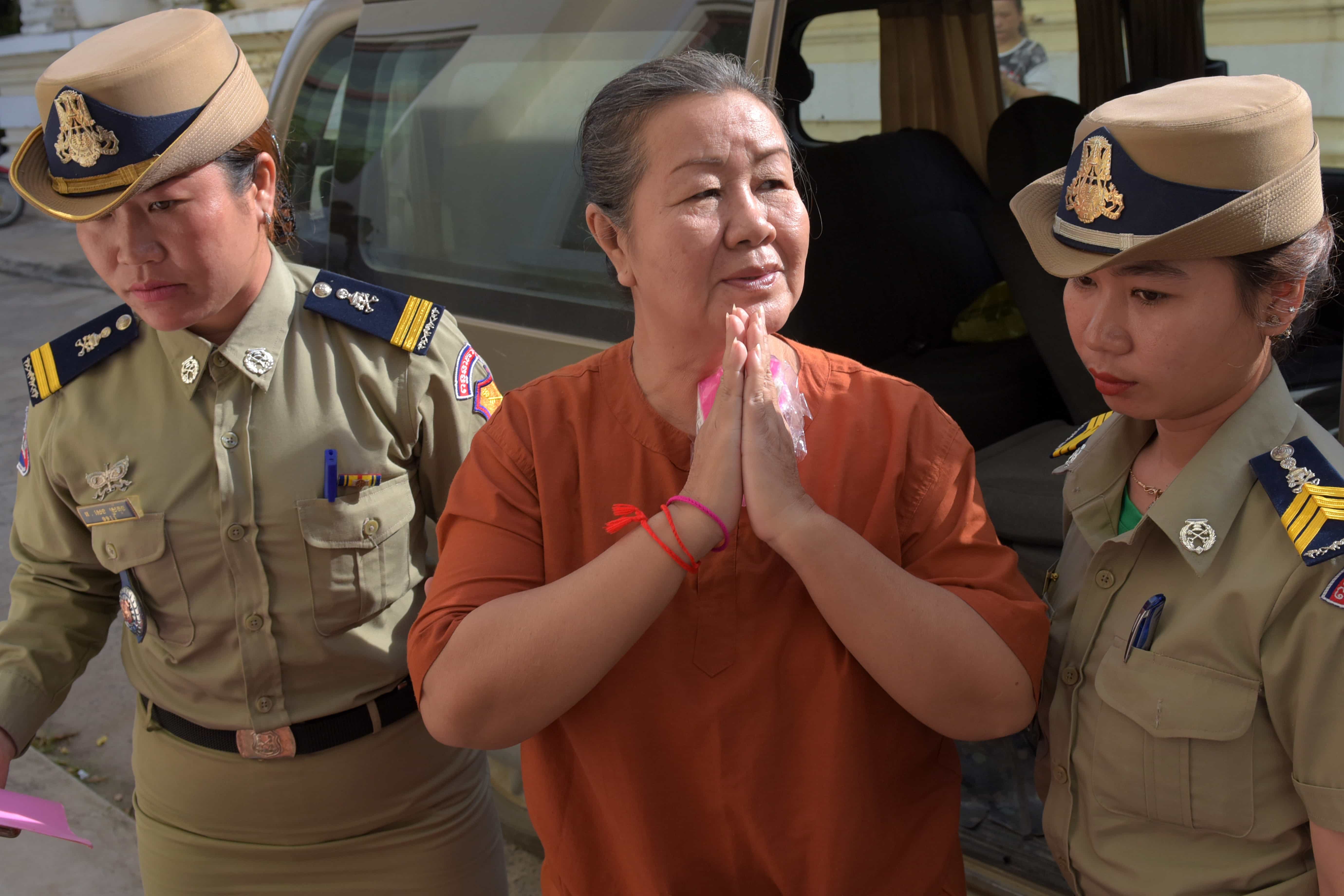 ADHOC 5 member, Lim Mony, escorted by police officials outside the appeals court in Phnom Penh, 30 August 2016, TANG CHHIN SOTHY/AFP/Getty Images