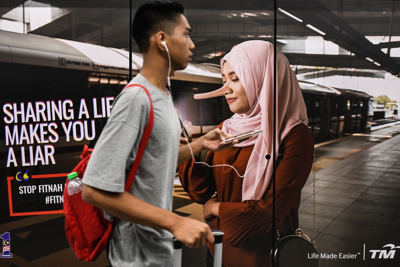 A commuter walks past an advertisement reading 'sharing a lie makes u a liar' at a train station in Kuala Lumpur, Malaysia, 26 March 2018, MOHD RASFAN/AFP/Getty Images