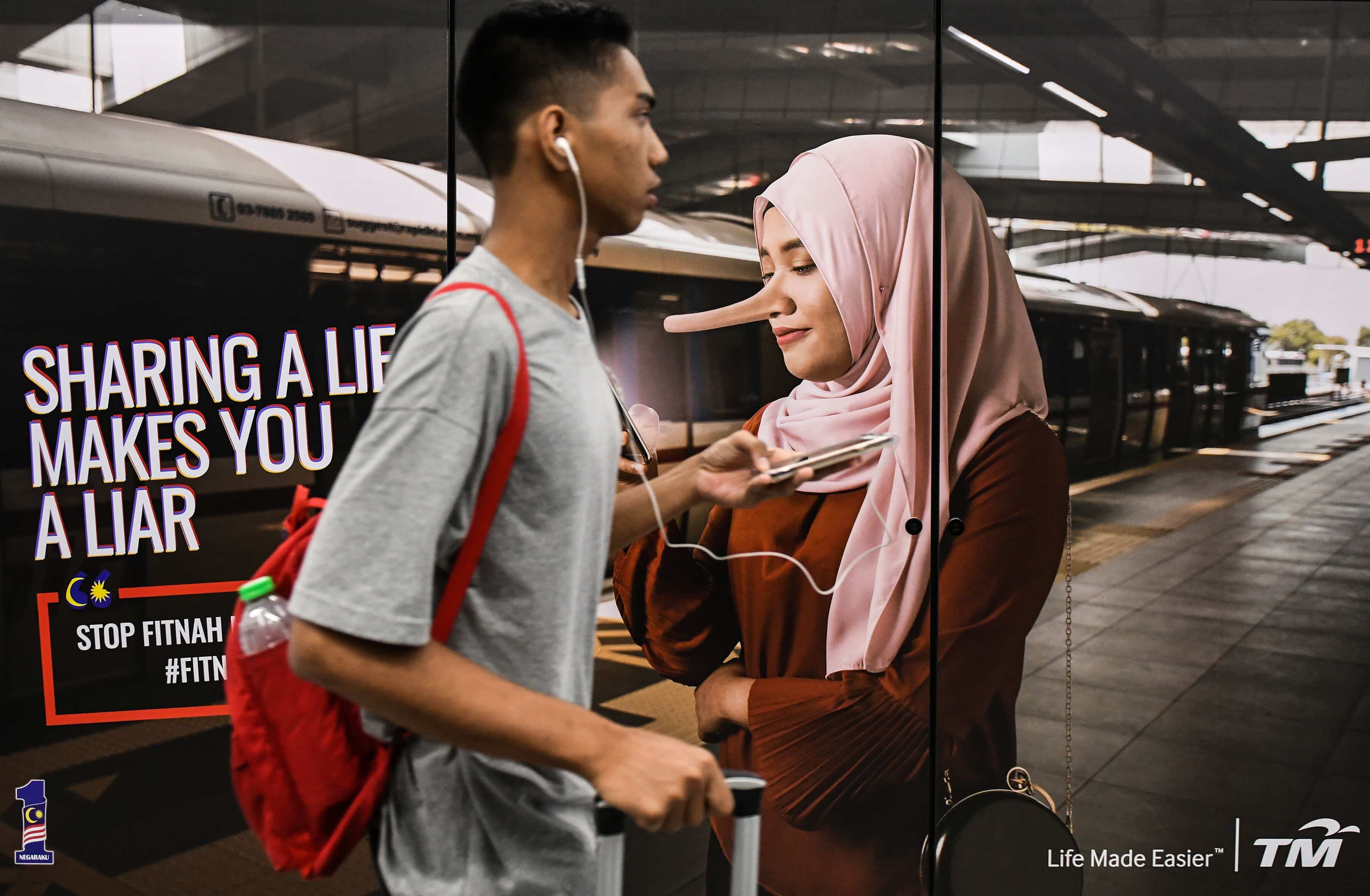 Commuter walks past anti "fake news" public service announcement,  Kuala Lumpur, Malaysia, 26 March 2018, MOHD RASFAN/AFP/Getty Images