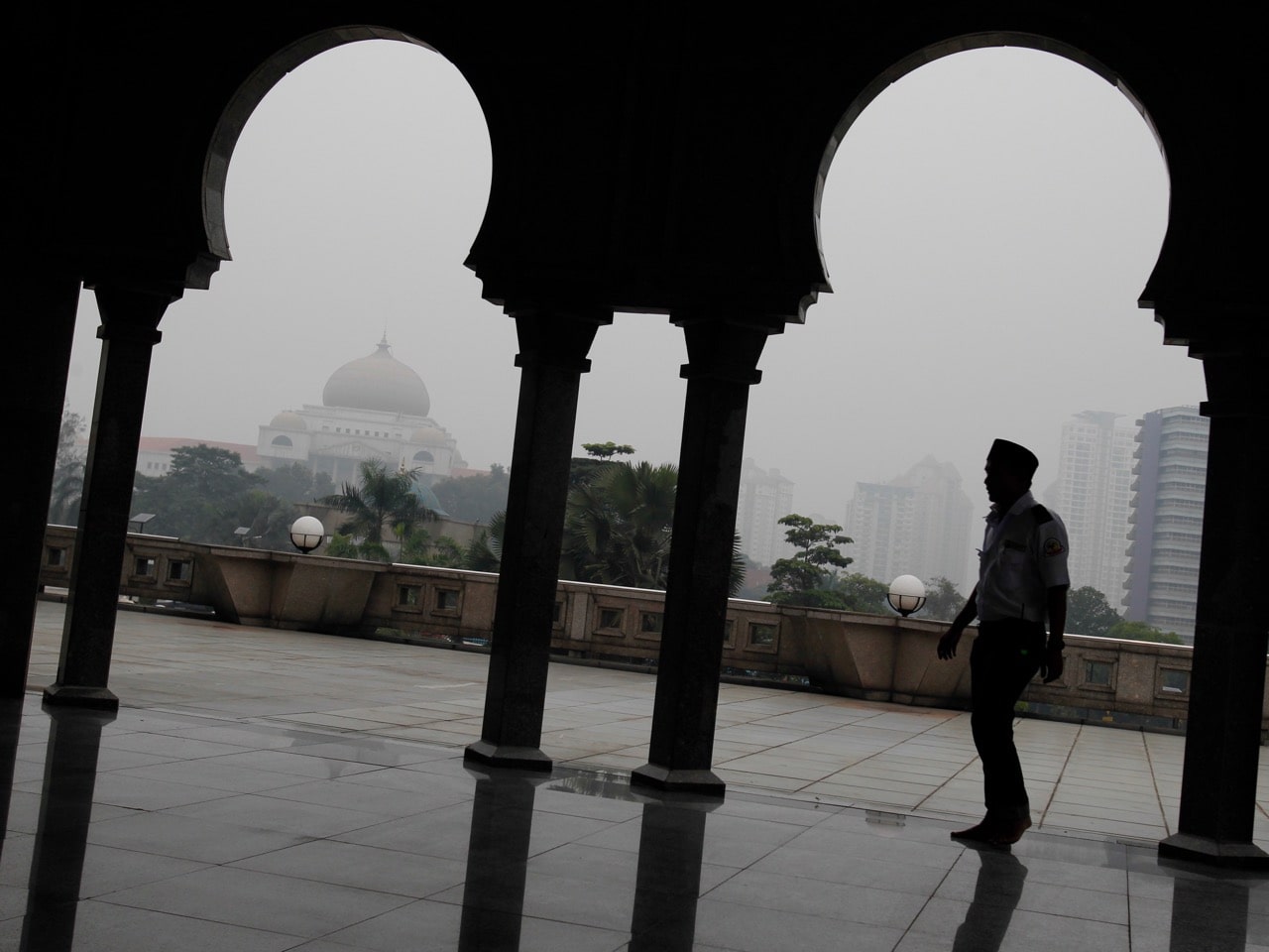A man is silhouetted against Malaysia's high court building, left, shrouded with haze in Kuala Lumpur, 19 October 2015, AP Photo/Joshua Paul