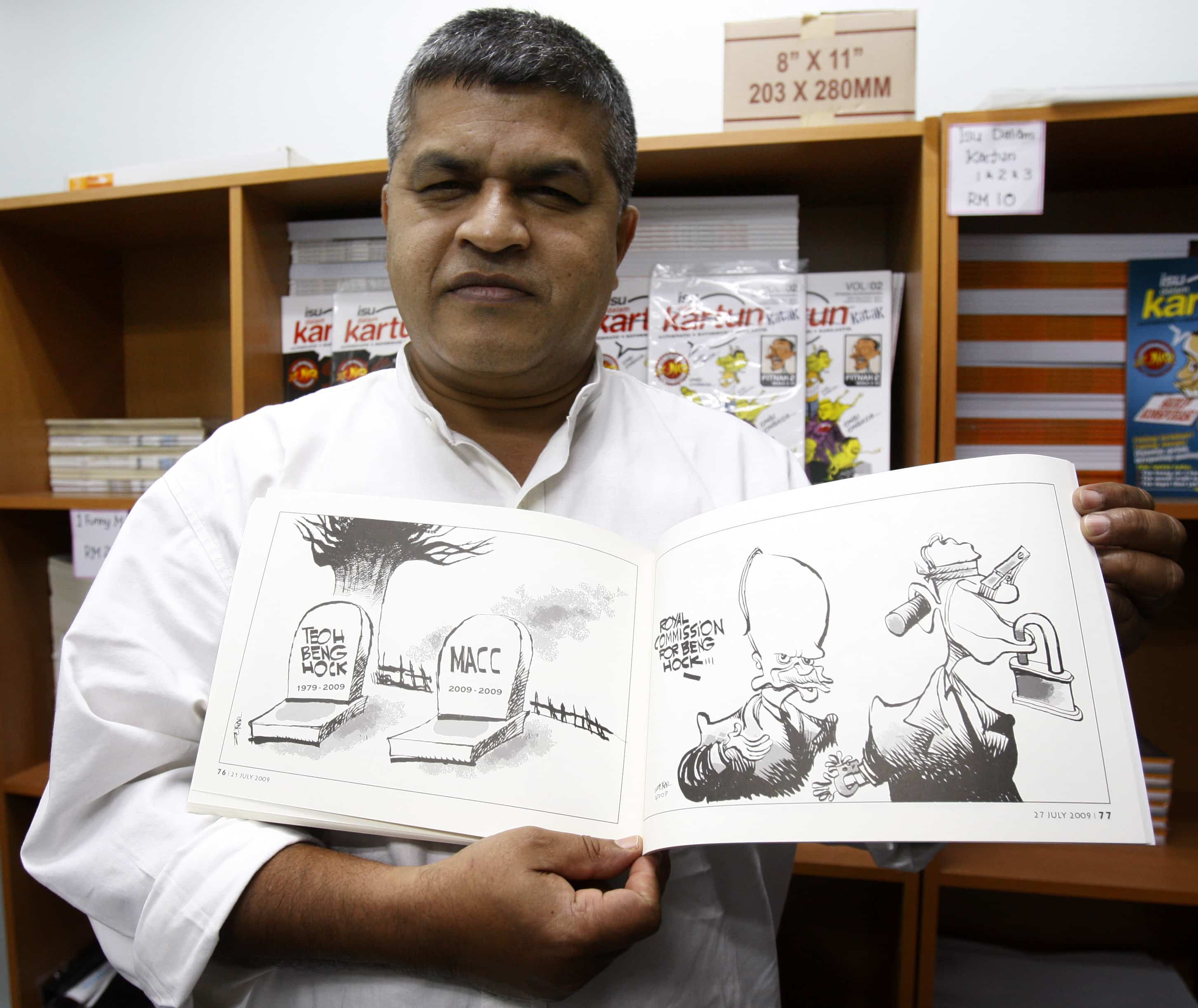 In this 25 June 2010 photo in Kuala Lumpur, Zunar holds a copy of the comic book that was then banned by the Malaysian Home Ministry, Ap/Lai Seng Sin