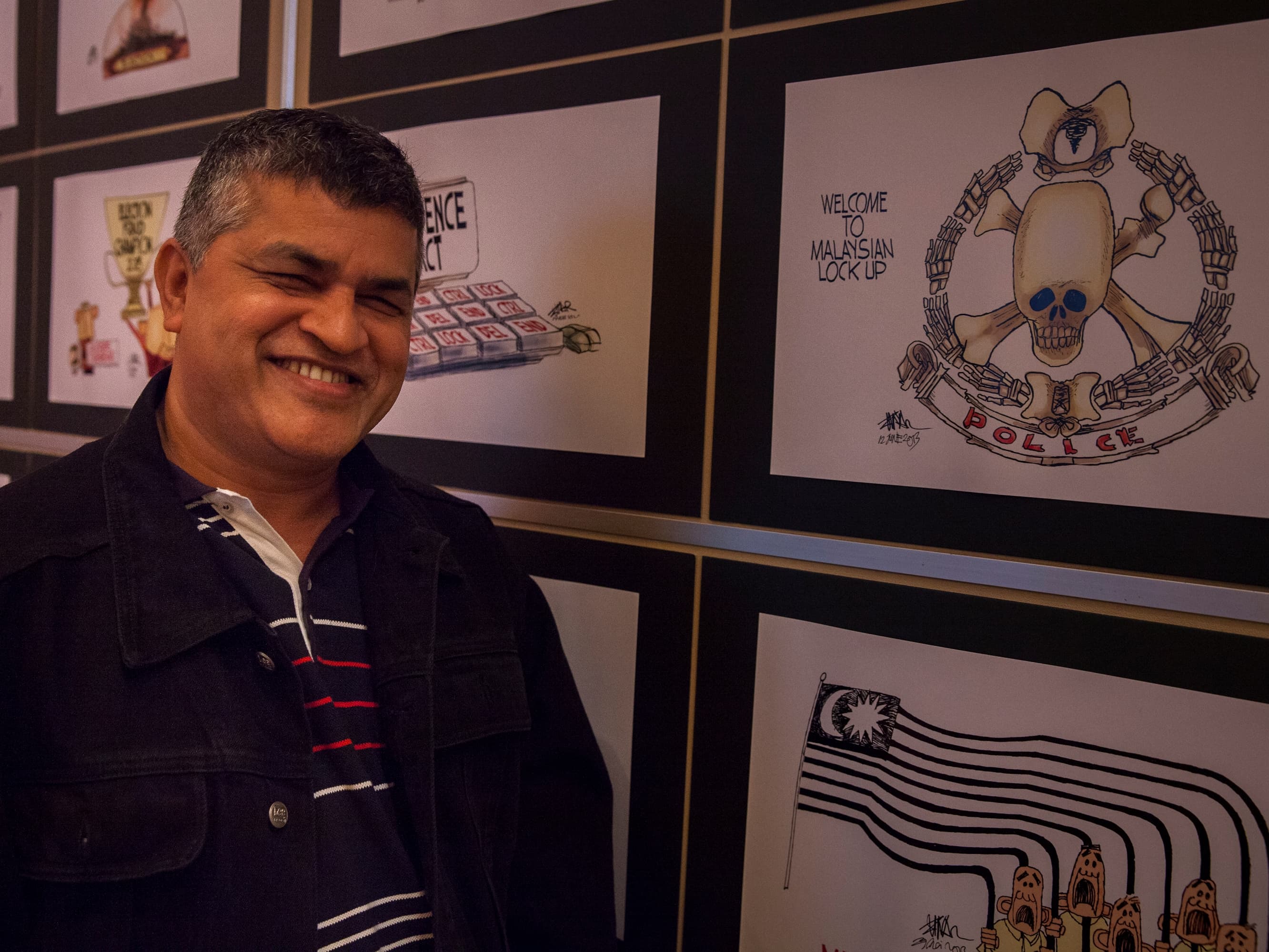 Political cartoonist Zunar poses with some of his artwork at the IFEX General Meeting in Phnom Penh, Cambodia, June 2013, @Jason Tanner/Erika Pineros