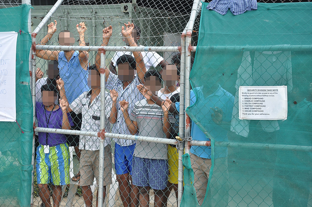 Asylum-seekers look through a fence at the Manus Island detention centre in Papua New Guinea March 21, 2014. , AAP/Eoin Blackwell/via REUTERS