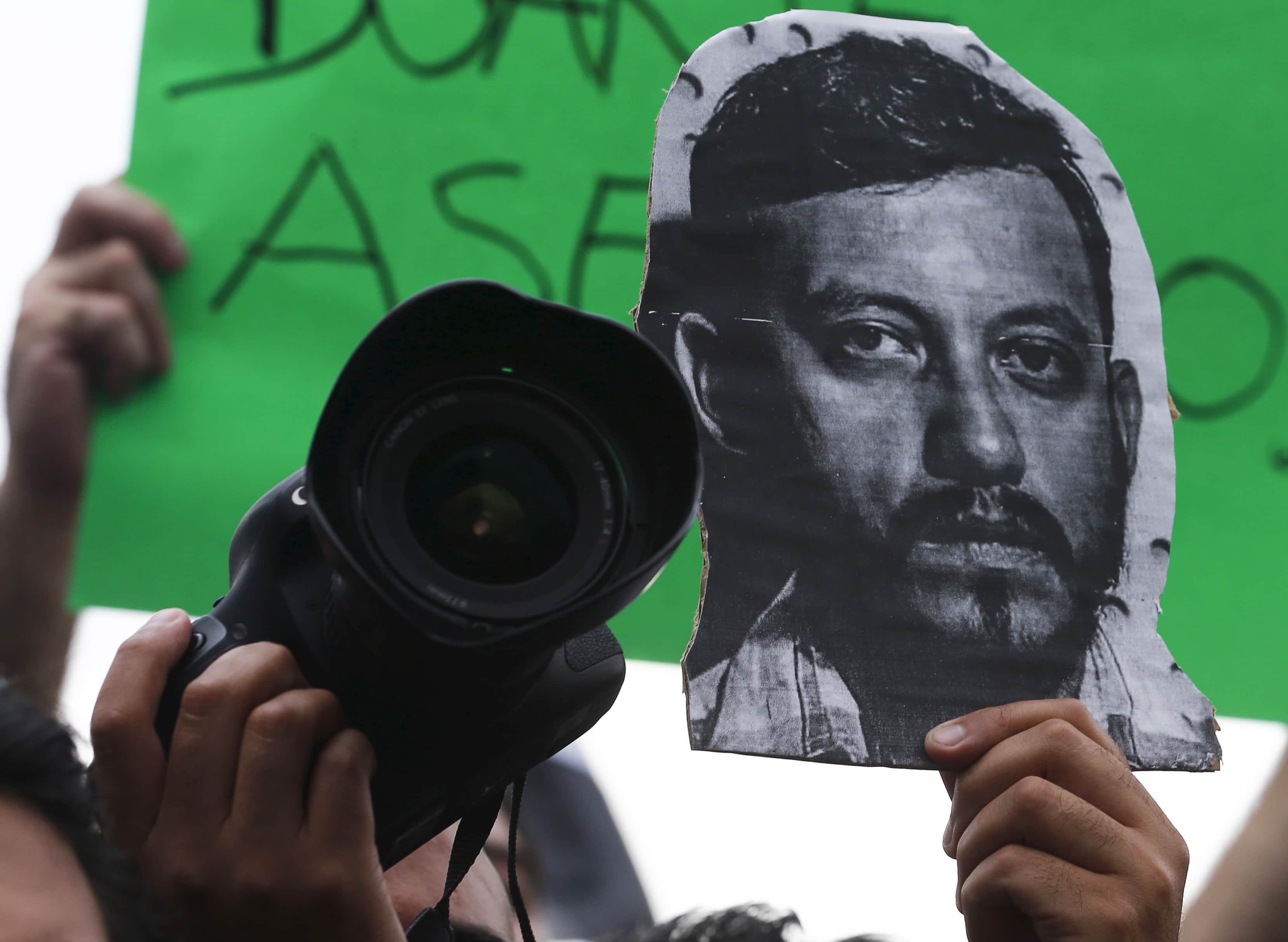 A photographer holds up his camera and a picture of photojournalist Ruben Espinosa during a protest against Espinosa's murder in Mexico City, REUTERS/Henry Romero